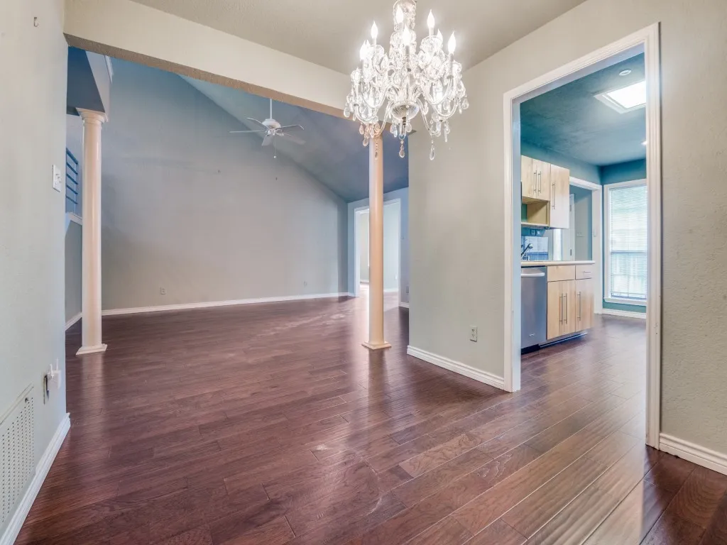 Formal dining area with ceiling fan, dark wood-type flooring, ornate columns, lofted ceiling, and a chandelier