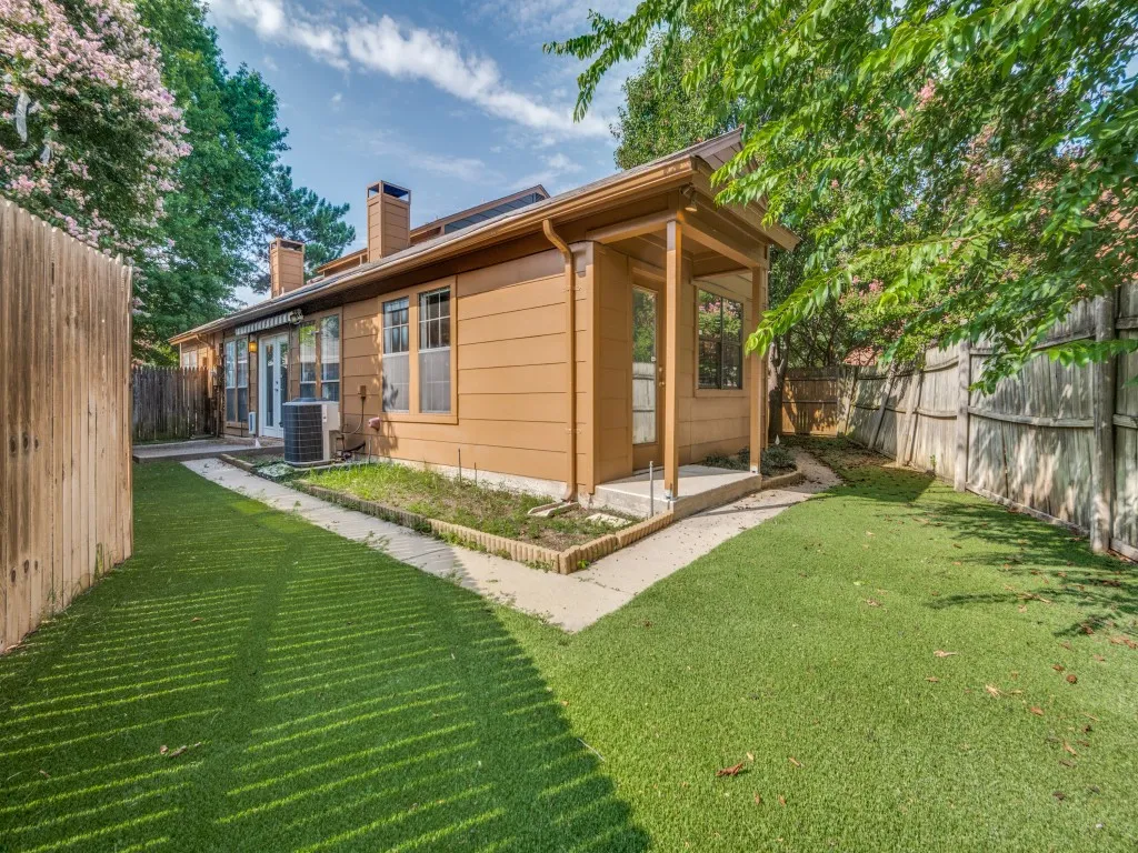 Rear view of house featuring artificial turf, wood fence and electric awnings.