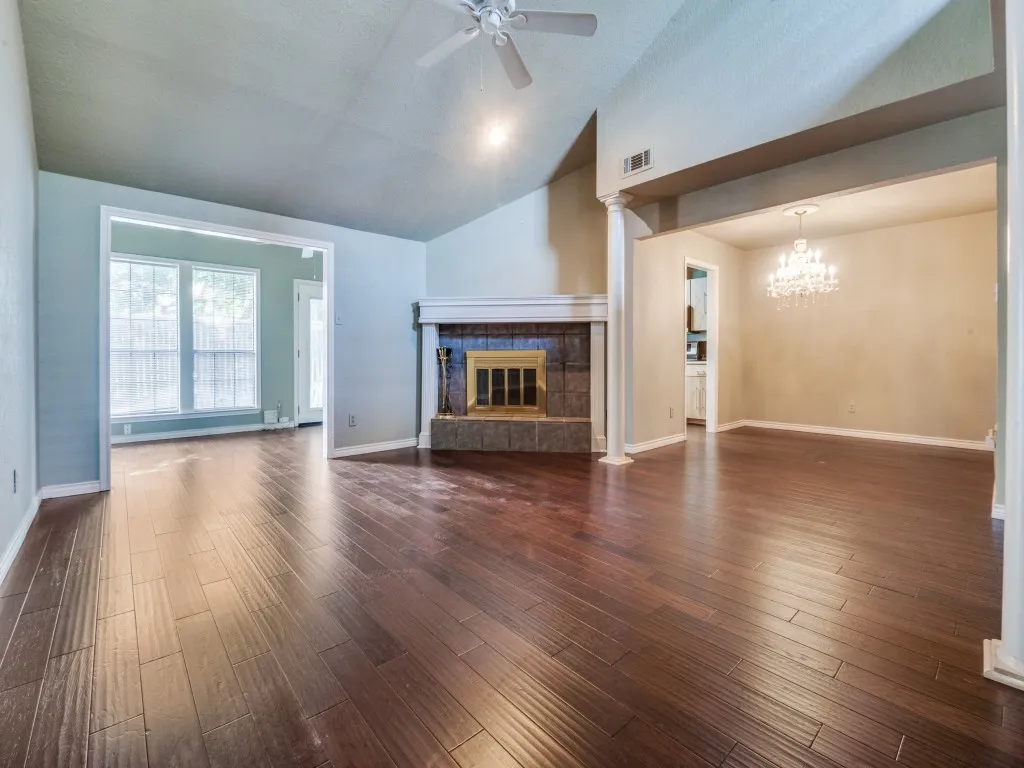 Formal living room featuring ceiling fan, a tile fireplace, dark wood-type flooring, a chandelier, and high vaulted ceiling