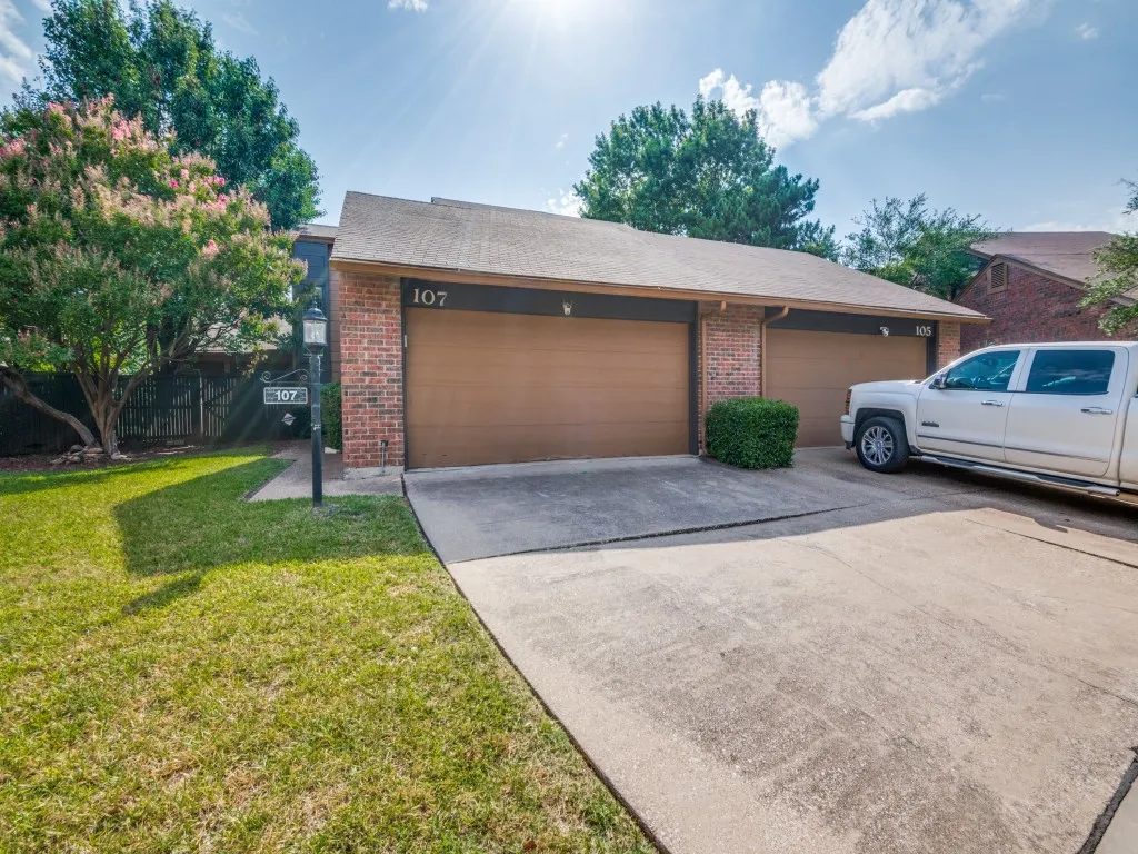 View of front of house with brick siding, concrete driveway, and an attached garage.