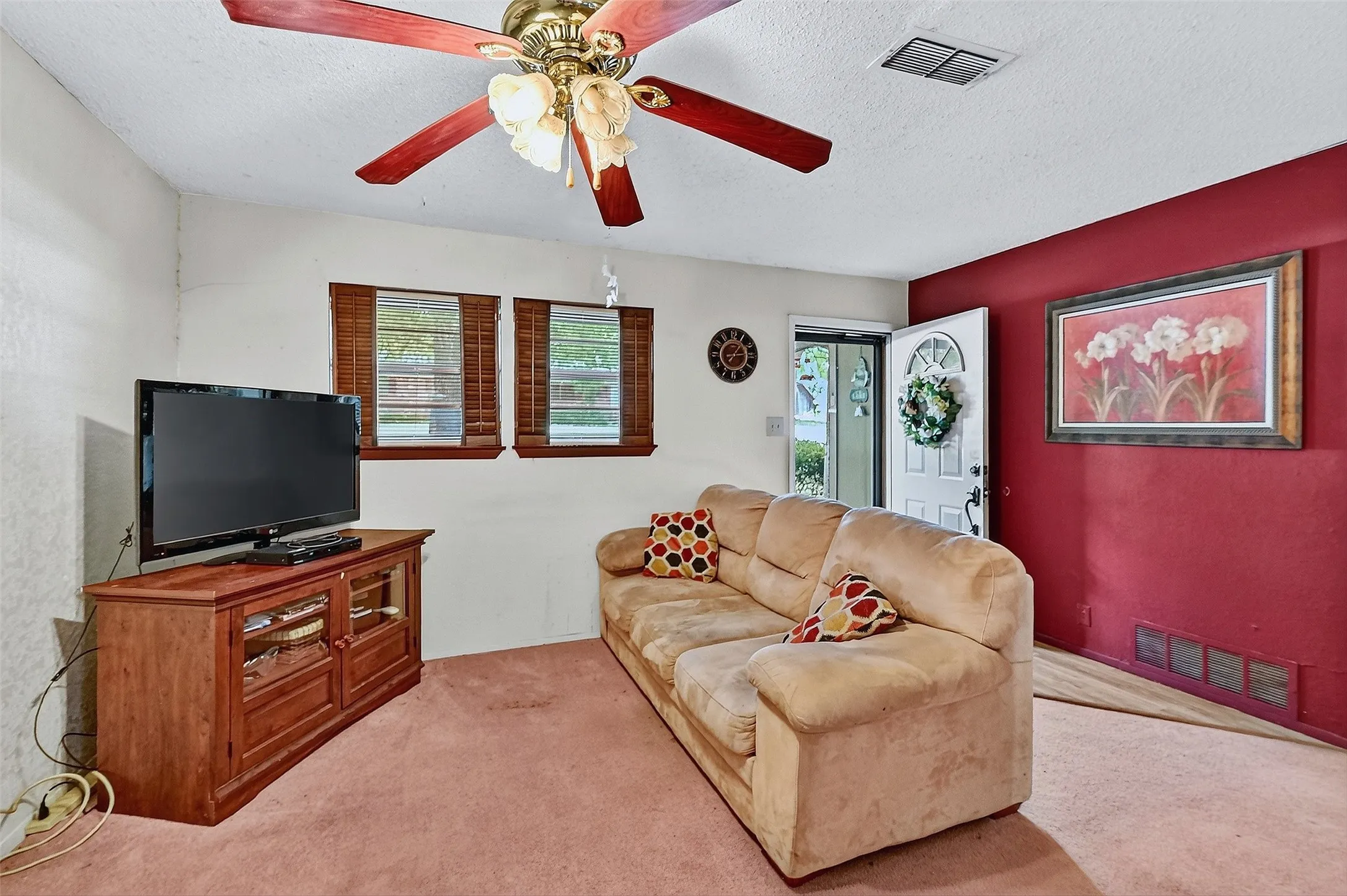 Carpeted living area with a ceiling fan and a textured ceiling