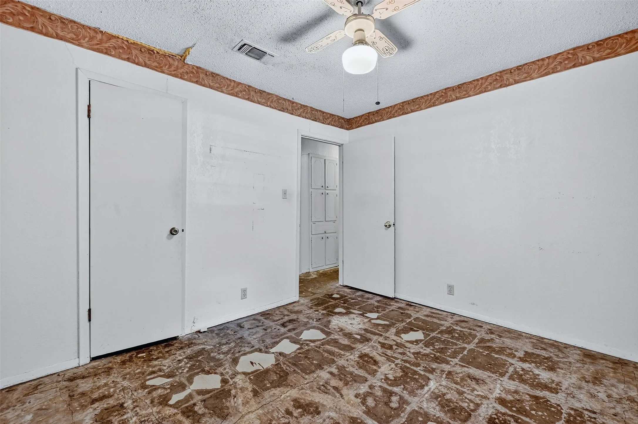Unfurnished bedroom featuring a textured ceiling and ceiling fan