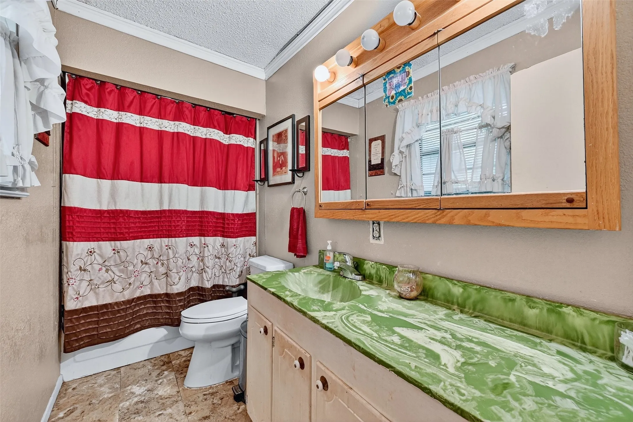 Full bathroom featuring crown molding, vanity, stone finish flooring, and a textured ceiling