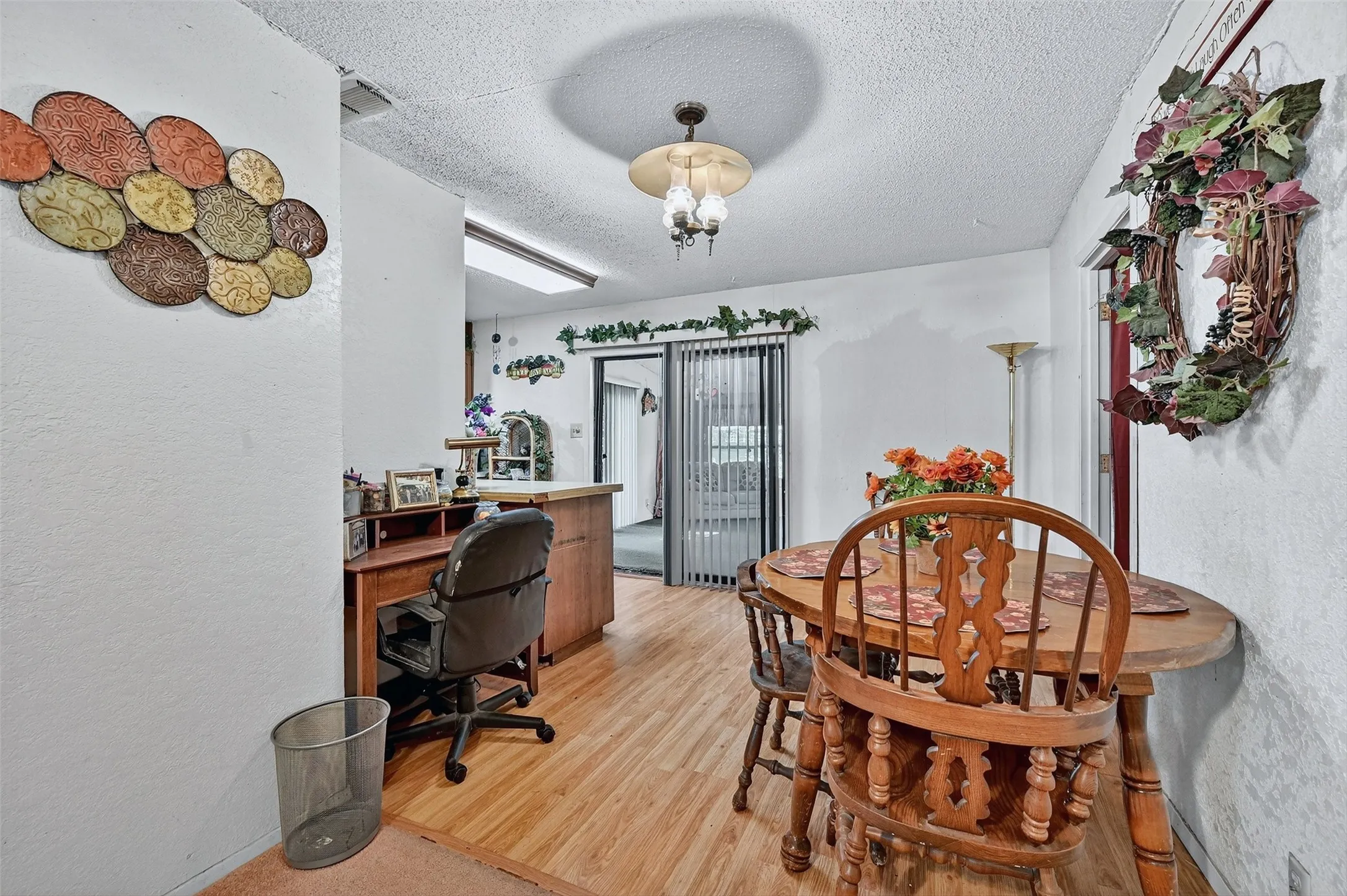 Office space featuring a textured ceiling, light wood-type flooring, and a textured wall