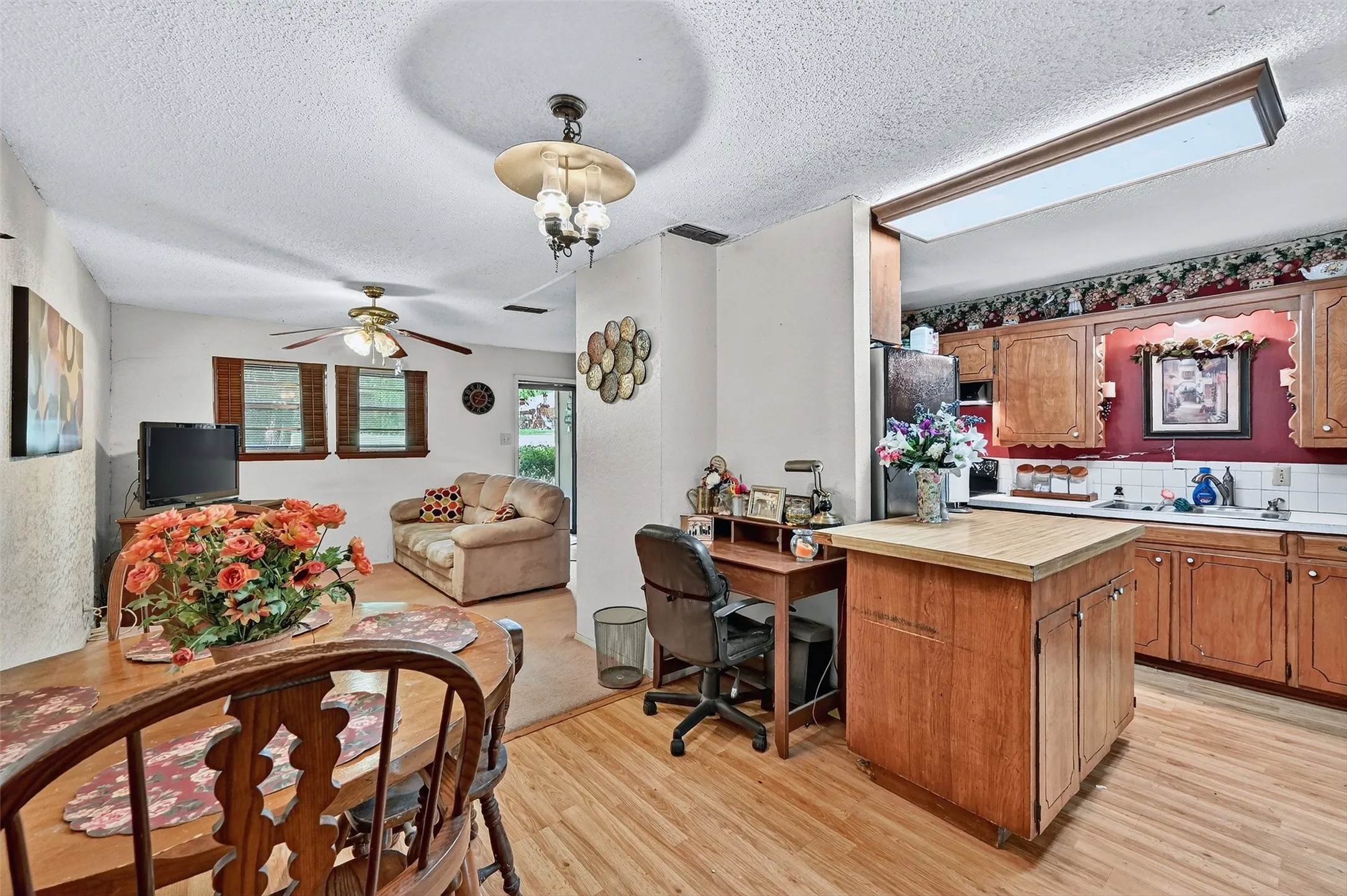 Kitchen with light wood-style flooring, light countertops, a textured ceiling, a ceiling fan, and open floor plan