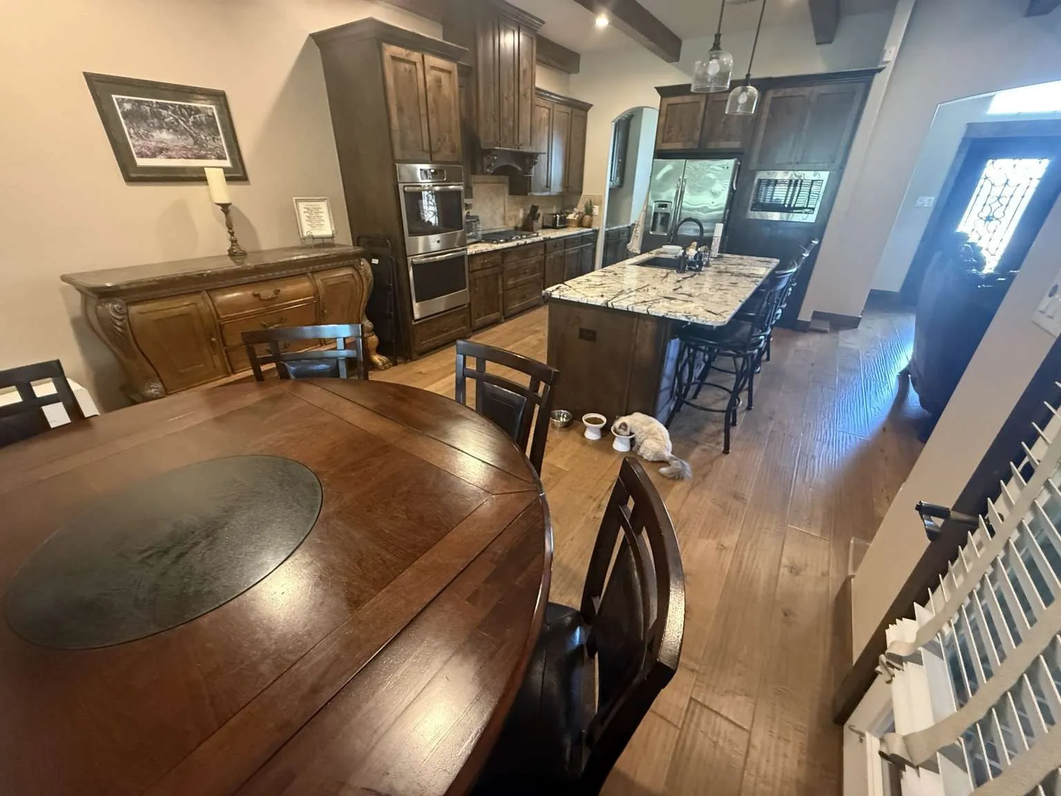 Kitchen with a kitchen island with sink, dark brown cabinets, light wood finished floors, stainless steel appliances, and a breakfast bar