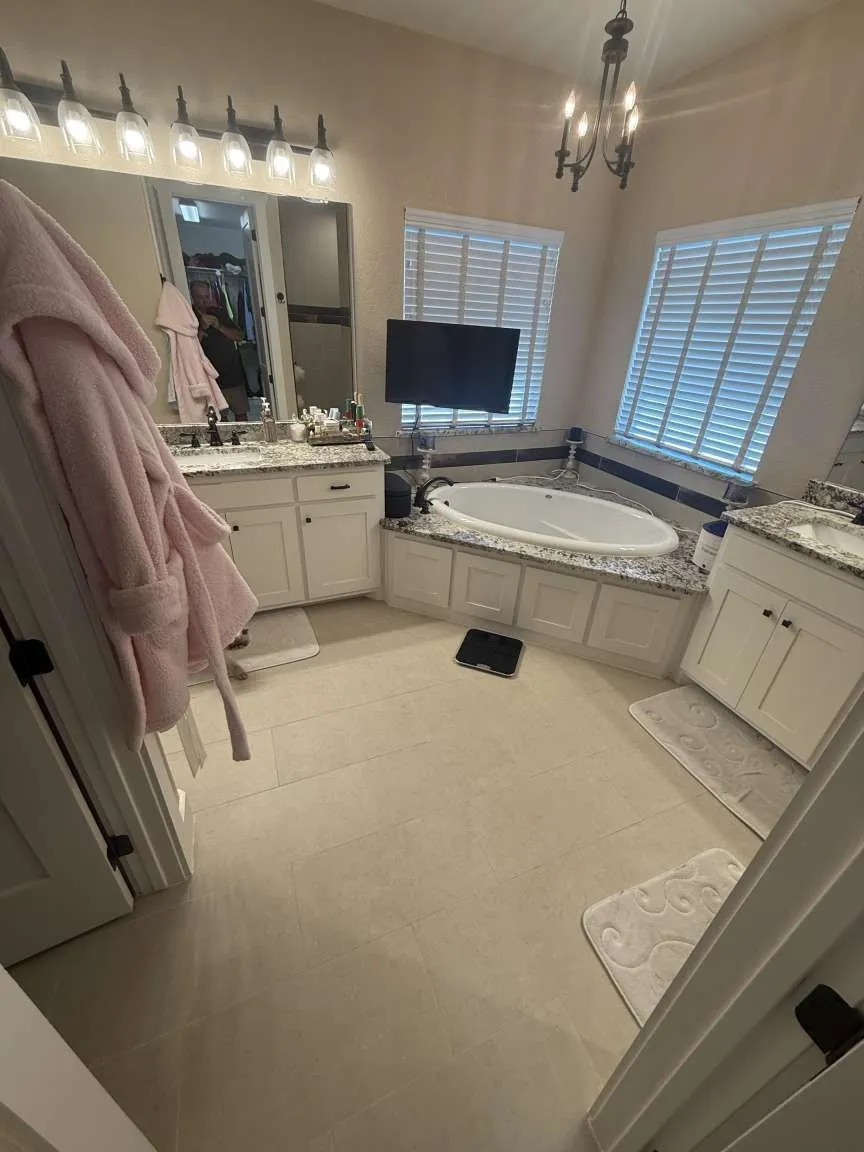 Bathroom with two vanities, a bath, a chandelier, and tile patterned floors