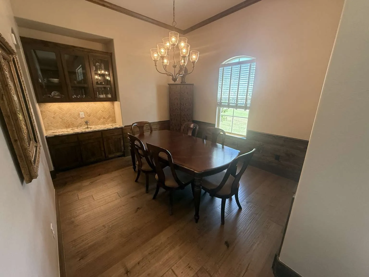 Dining space with ornamental molding, wainscoting, wood finished floors, and a chandelier