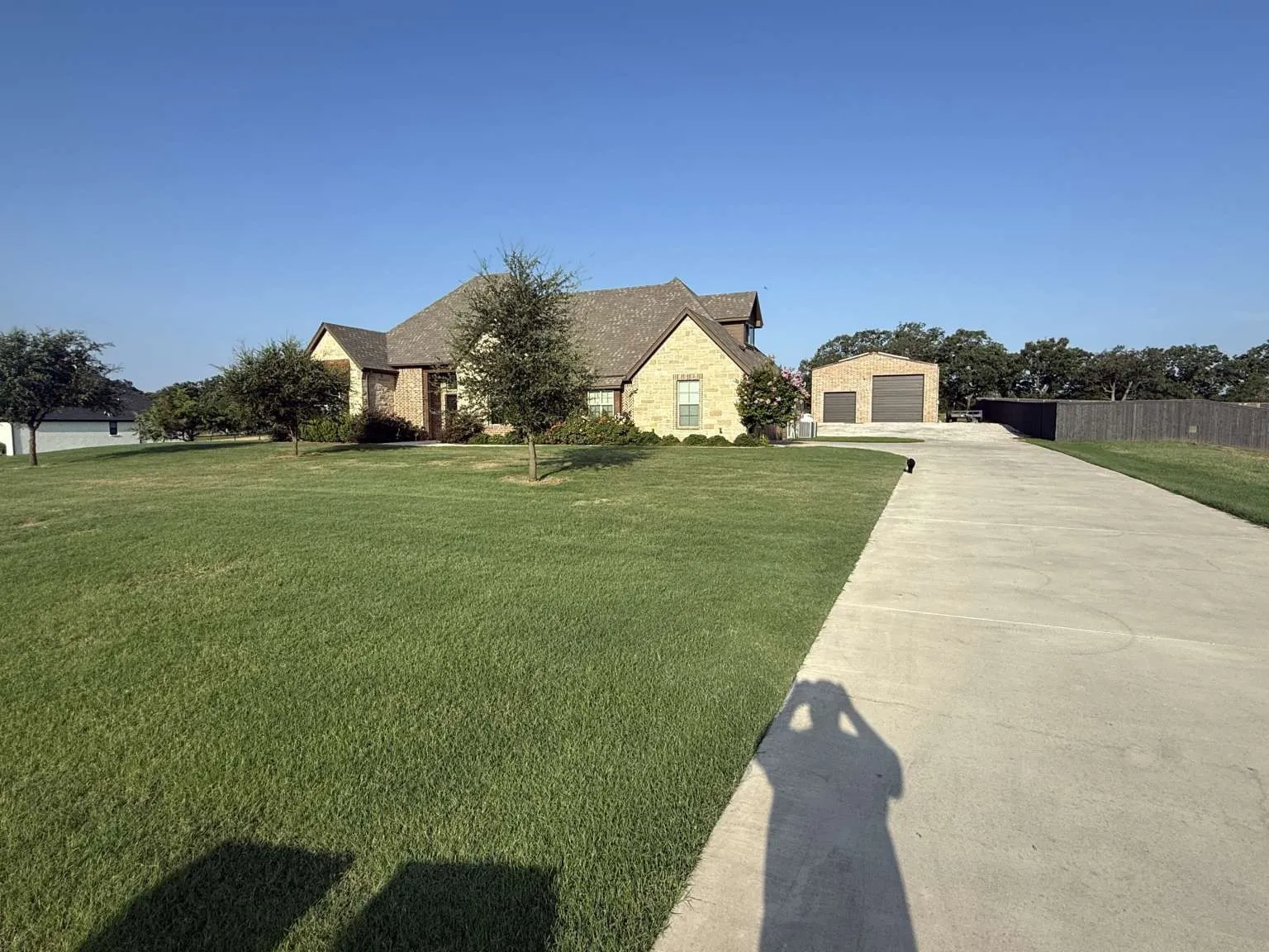 French provincial home with stone siding, an outbuilding, a detached garage, and driveway