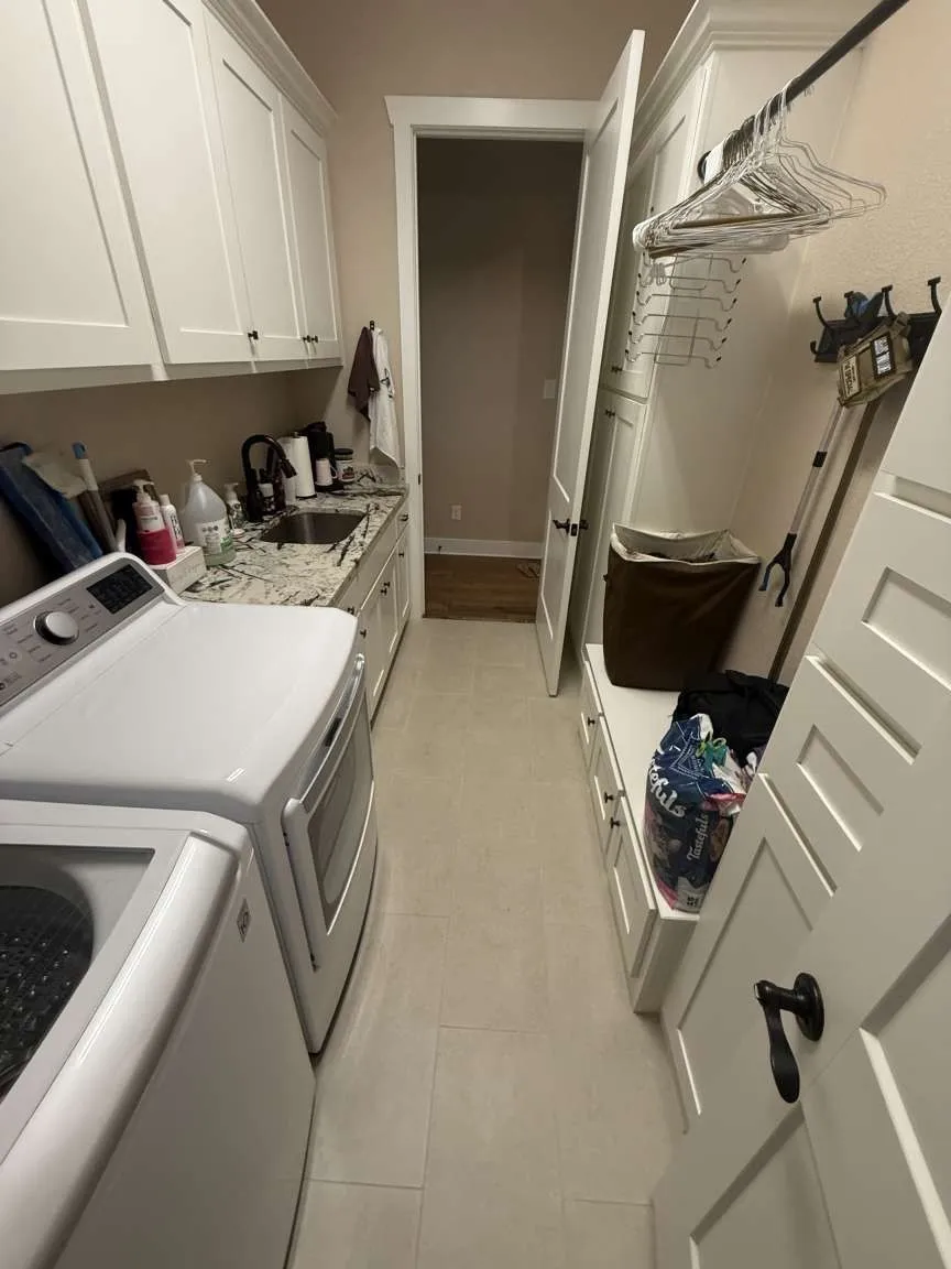 Washroom with cabinet space, washing machine and clothes dryer, and light tile patterned floors