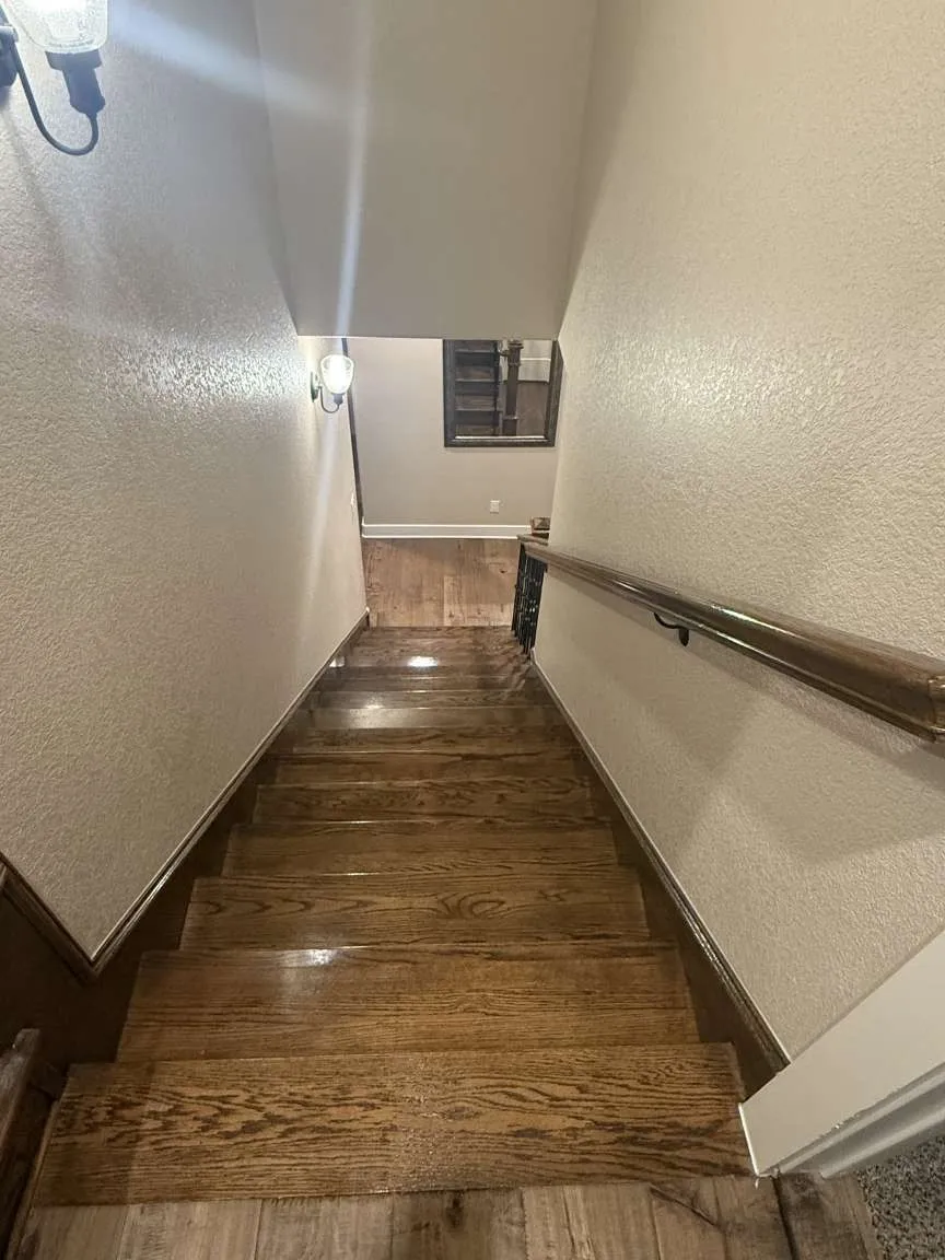 Stairs featuring hardwood / wood-style flooring and a textured wall