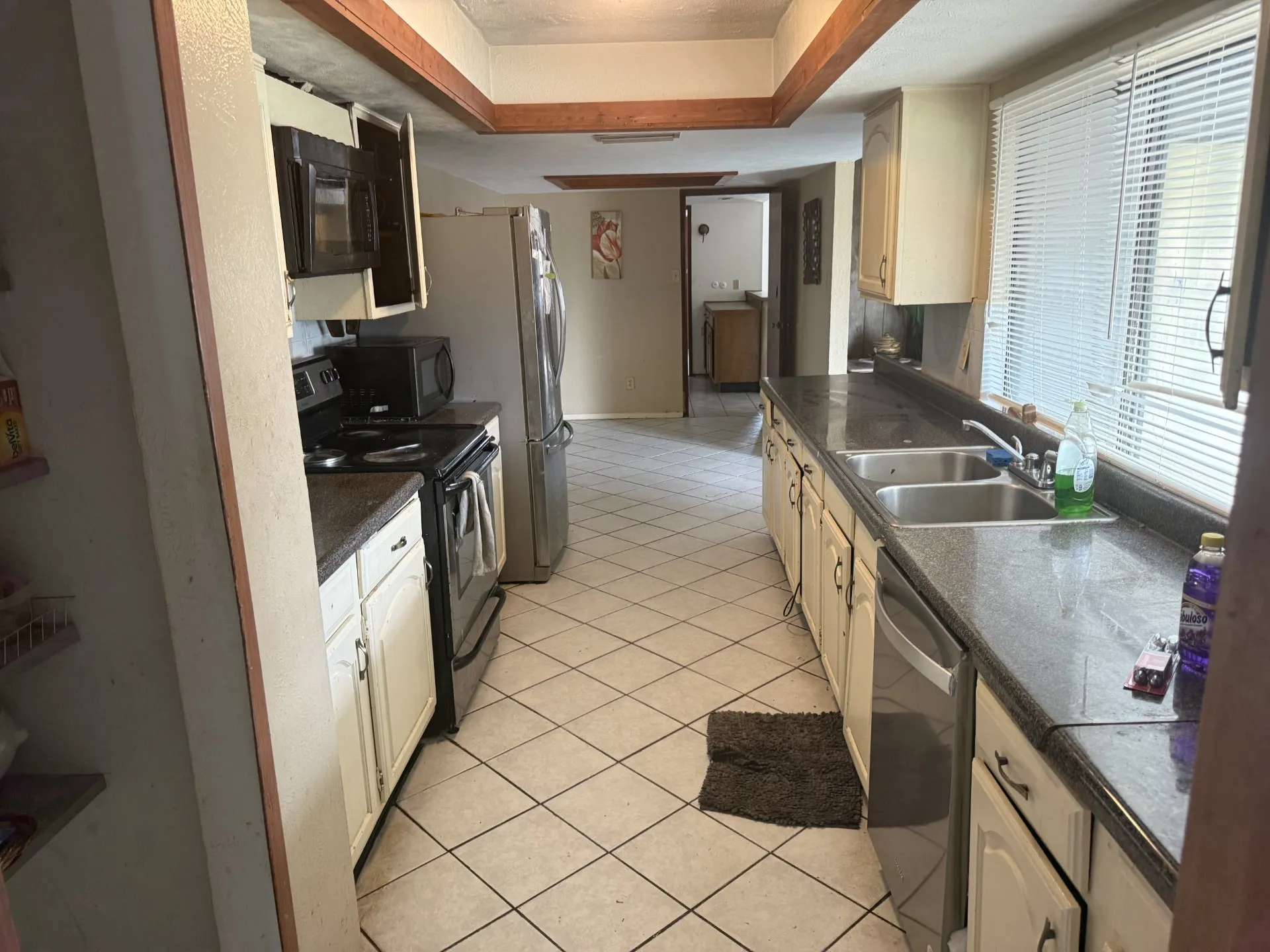 Kitchen with black appliances, dark countertops, light tile patterned floors, and cream cabinets