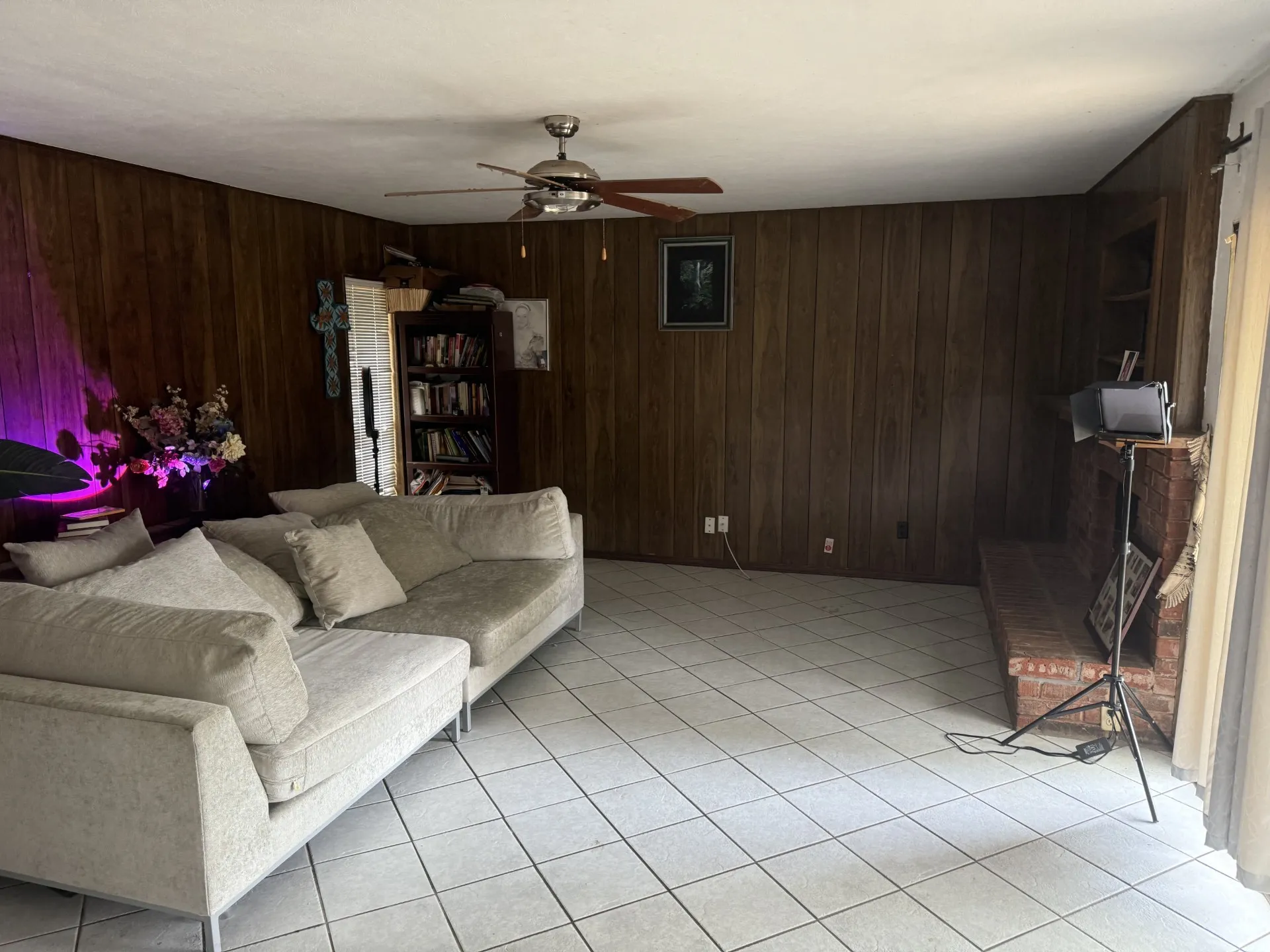 Living area with wooden walls, a ceiling fan, and light tile patterned floors