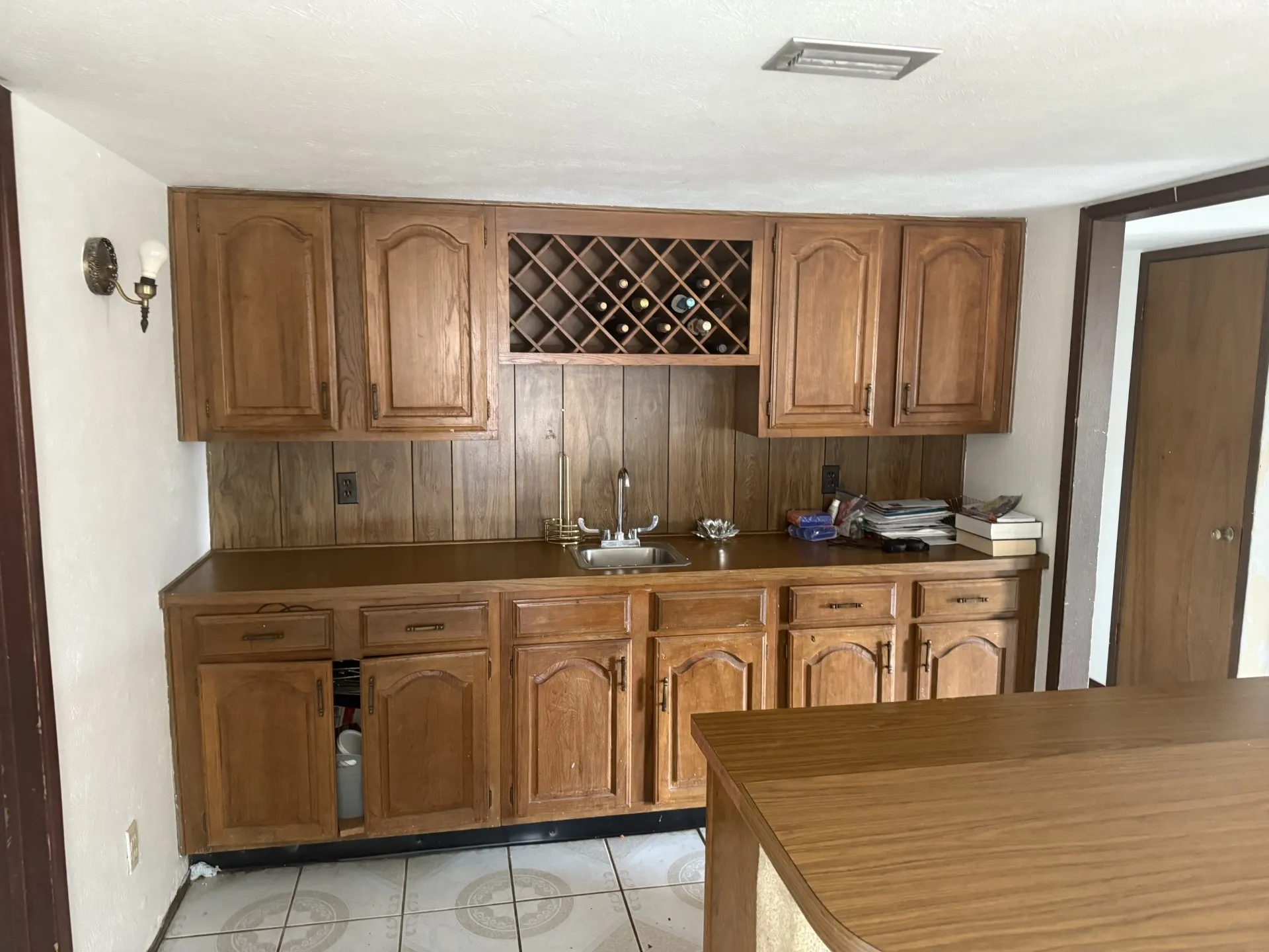 Kitchen featuring brown cabinetry, light tile patterned floors, and dark countertops