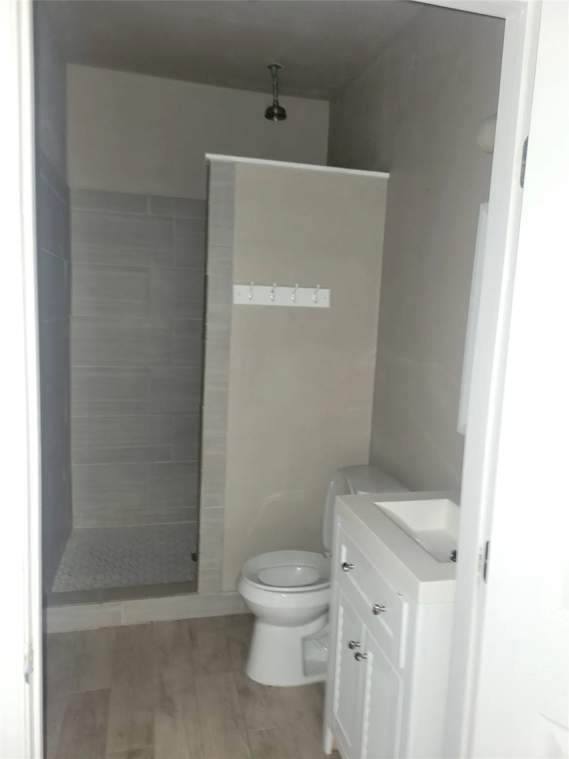 Bathroom featuring vanity, a tile shower, and wood finished floors