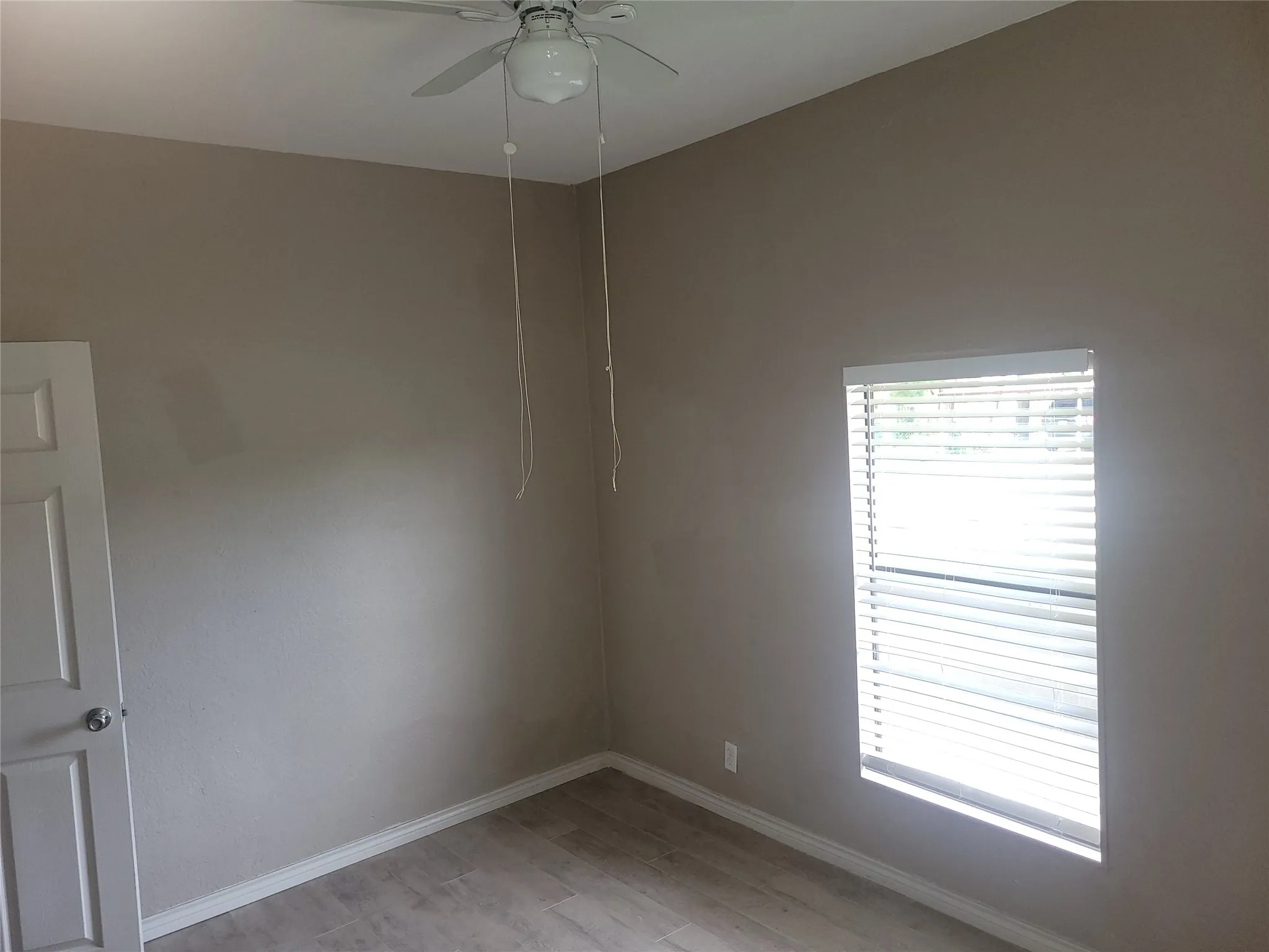 Empty room with a ceiling fan and light wood-style flooring
