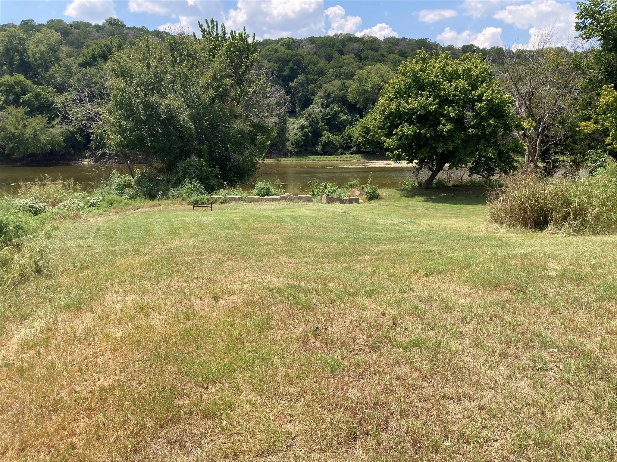 View of grassy yard with a water view and a view of trees