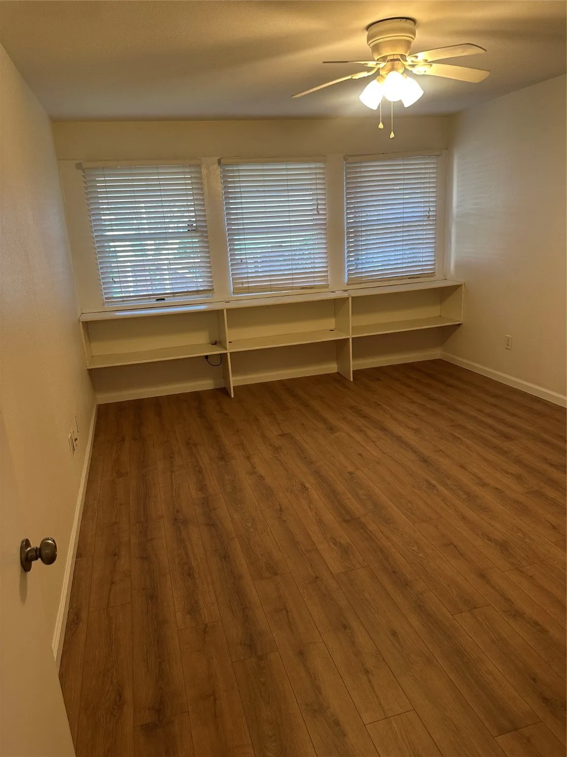 Bedroom  with shelving, featuring wood finished floors, a ceiling fan, and healthy amount of natural light
