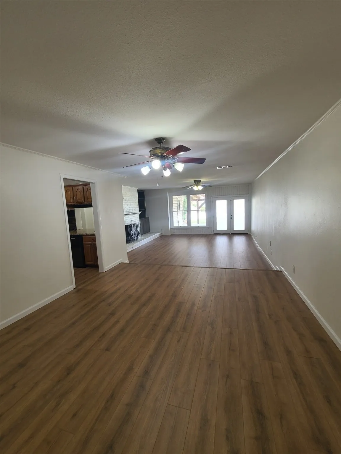 Den with a ceiling fan, dark wood-style flooring, a textured ceiling, a fireplace, and french doors