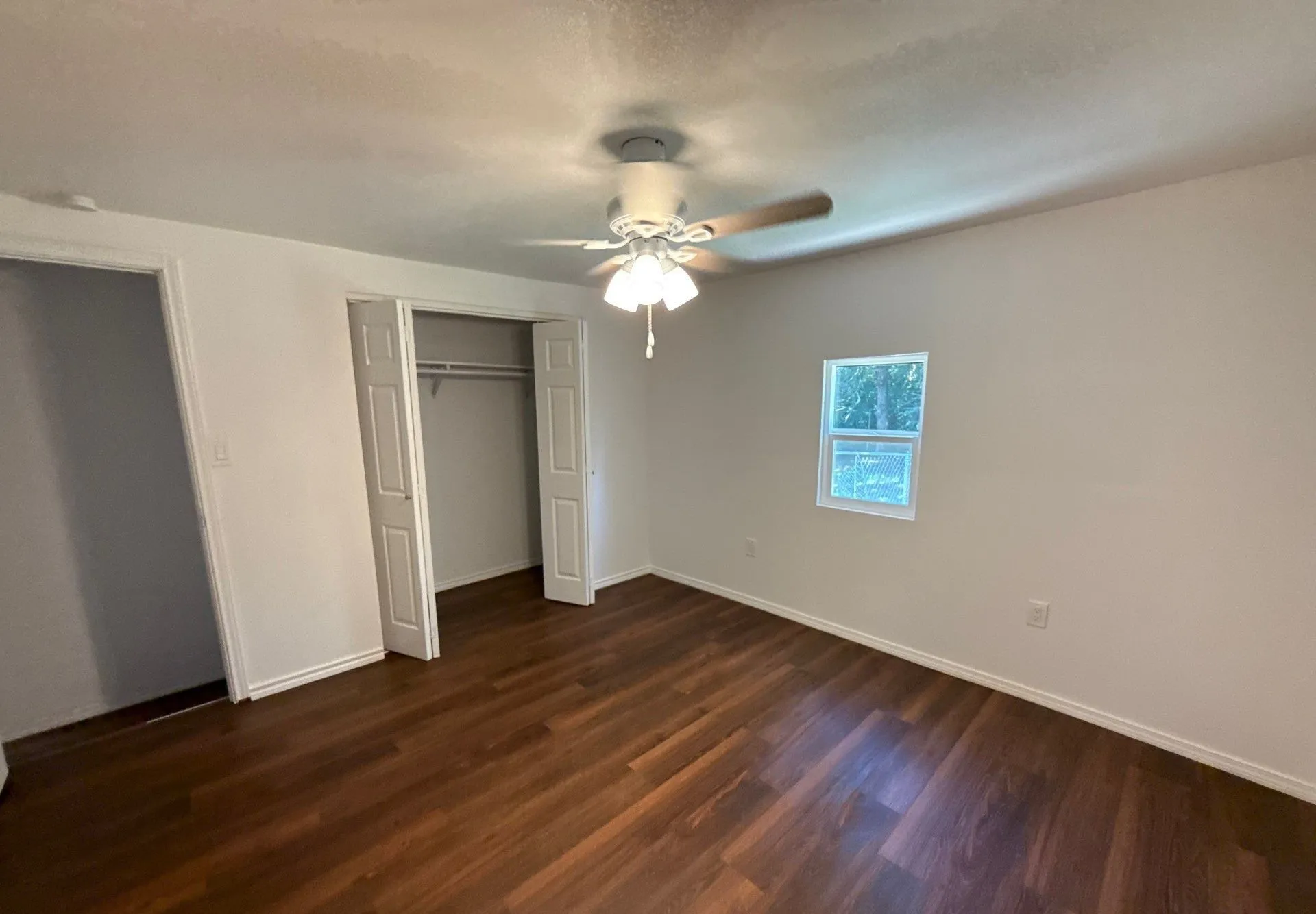 Unfurnished bedroom with dark wood finished floors, a closet, and ceiling fan