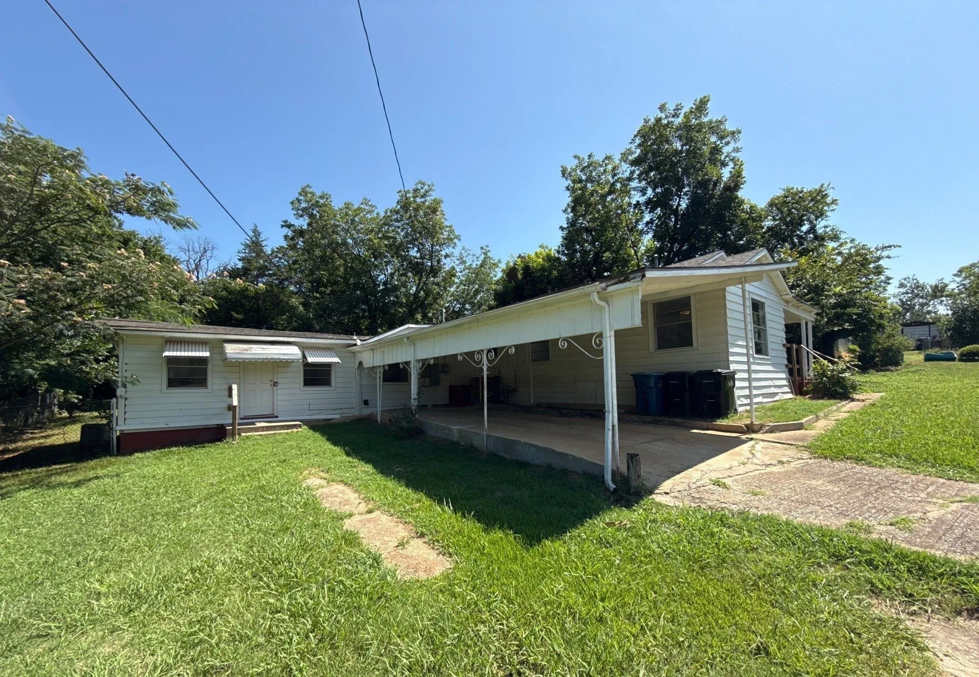 Rear view of house with an attached carport, driveway, and a lawn