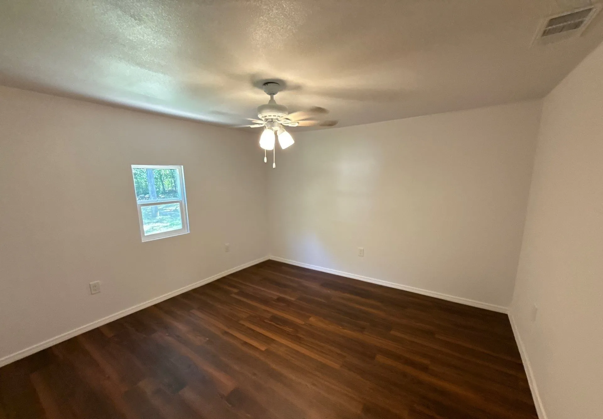 Unfurnished room featuring dark wood-style floors and a ceiling fan