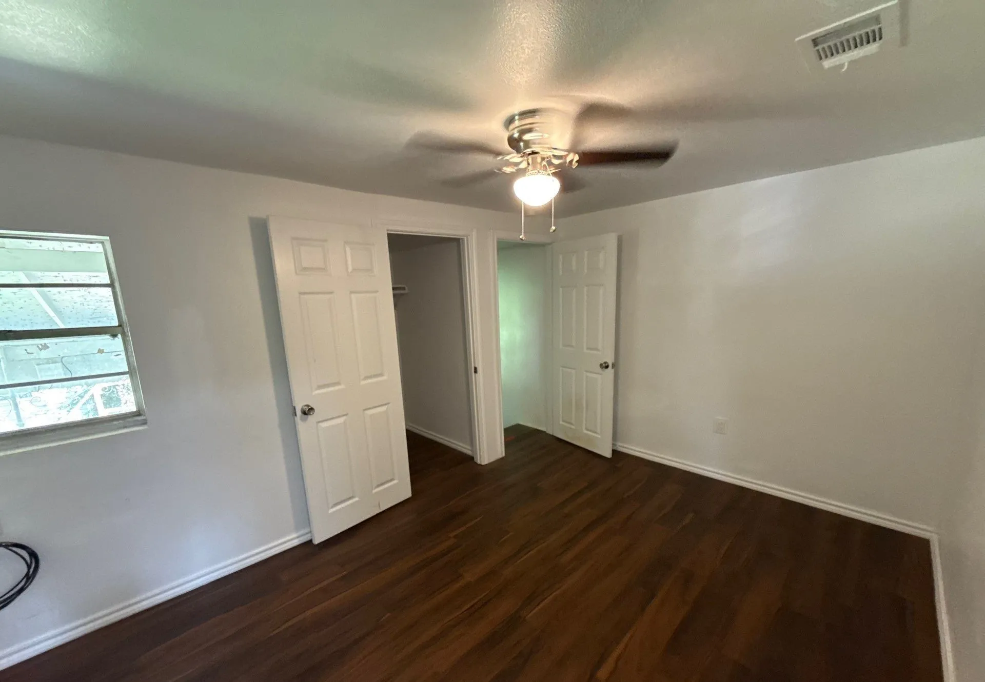 Unfurnished bedroom with dark wood-style flooring, a ceiling fan, and a closet