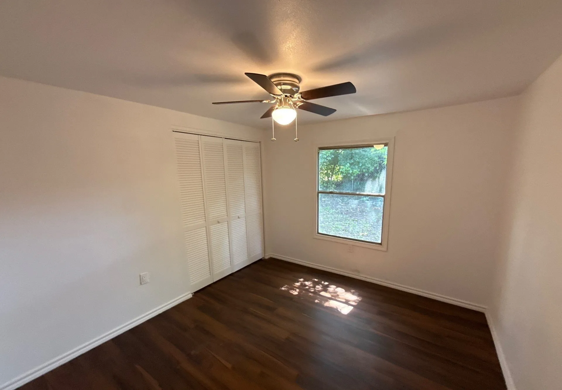 Unfurnished bedroom with dark wood-type flooring, a closet, and ceiling fan