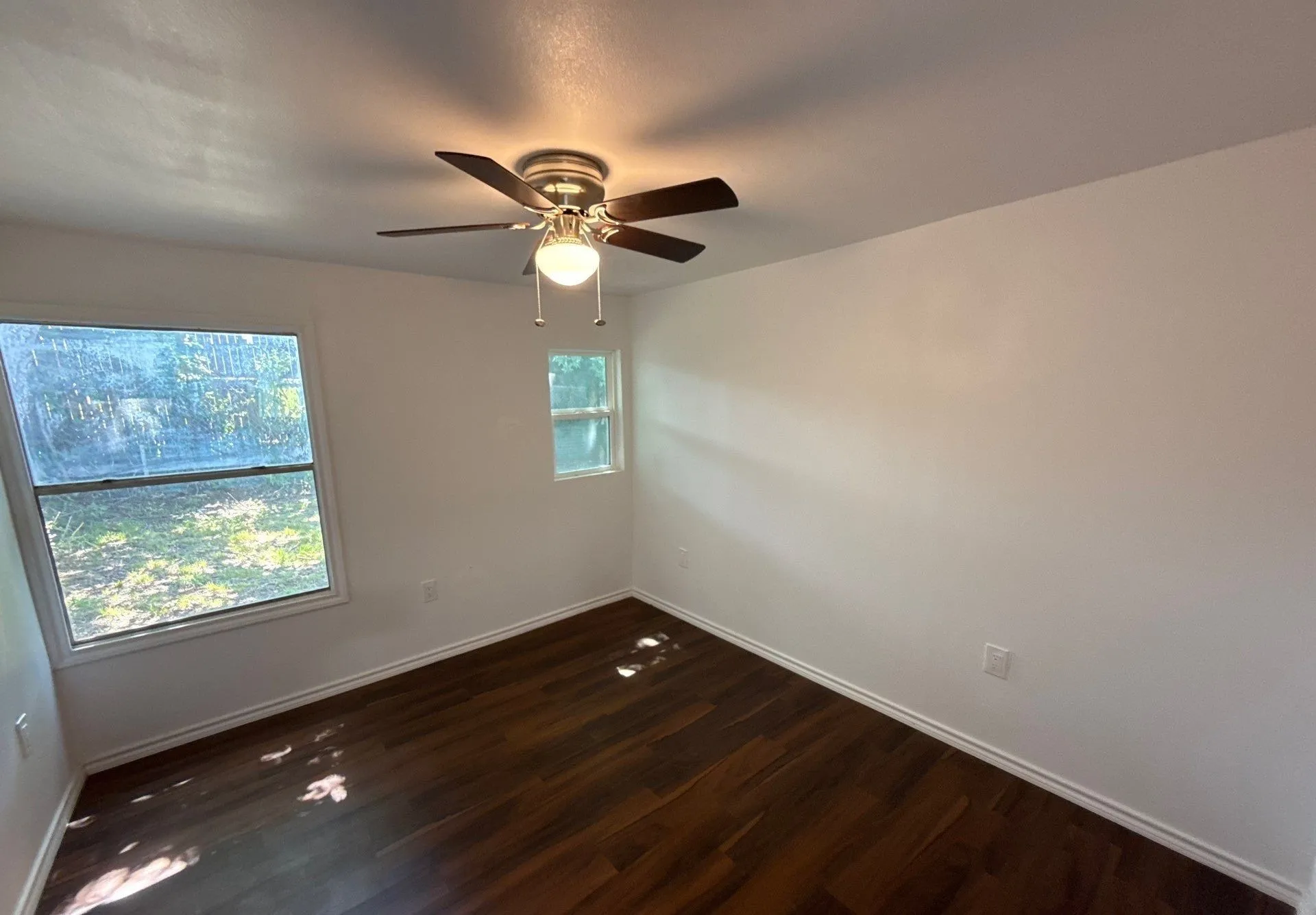 Unfurnished room featuring dark wood-type flooring and ceiling fan