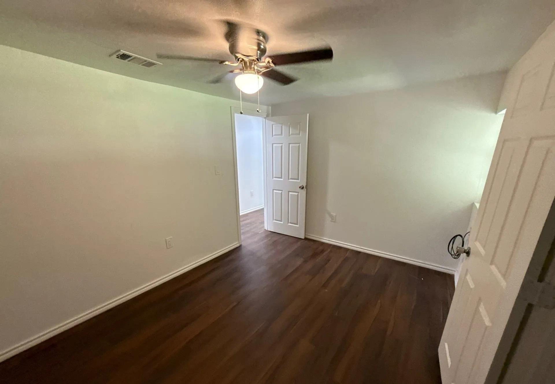 Empty room with dark wood-style floors and ceiling fan