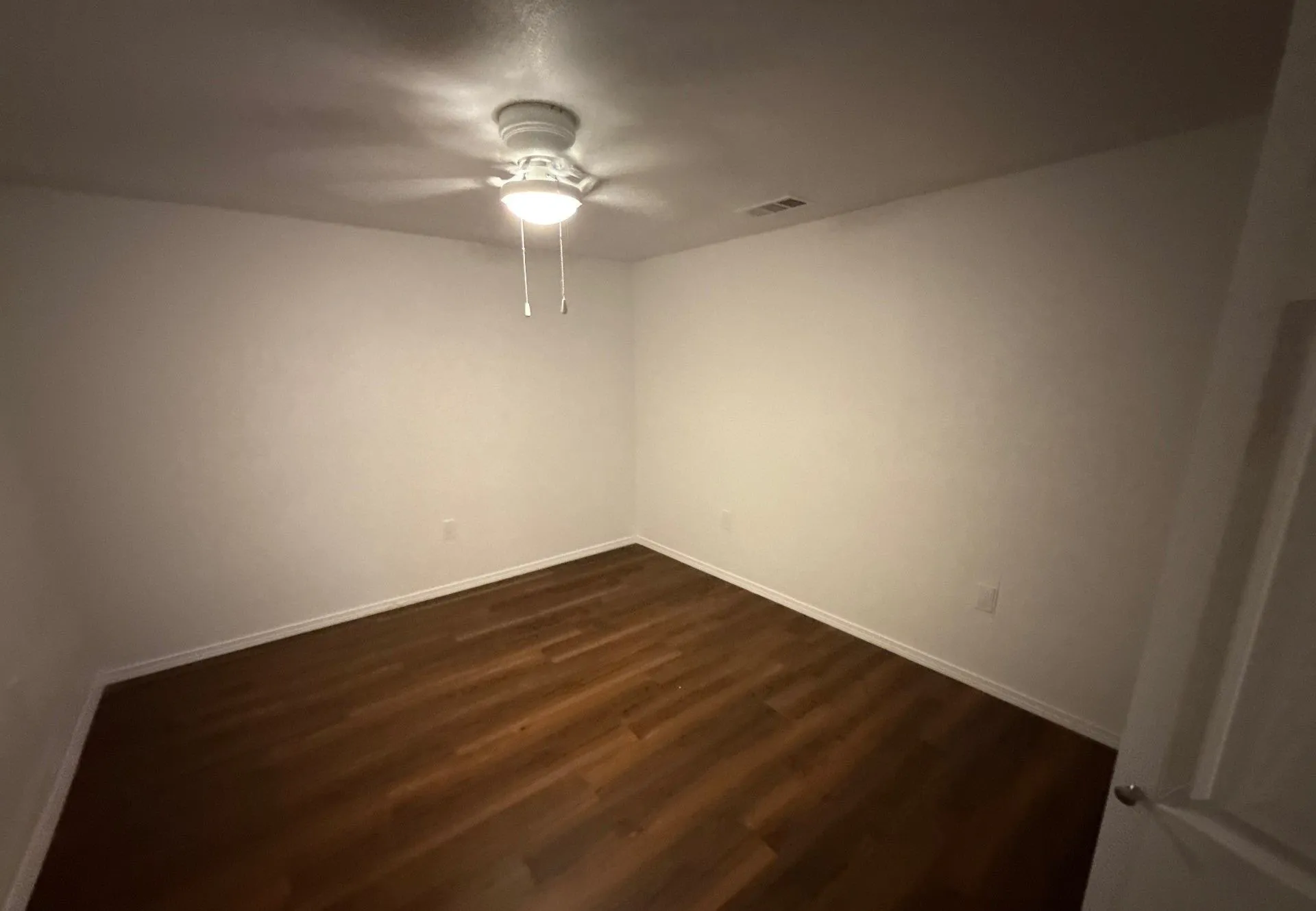 Spare room featuring a ceiling fan and dark wood finished floors