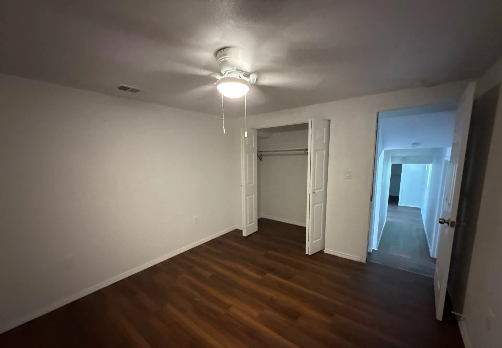 Unfurnished bedroom featuring dark wood-style flooring, a closet, and ceiling fan