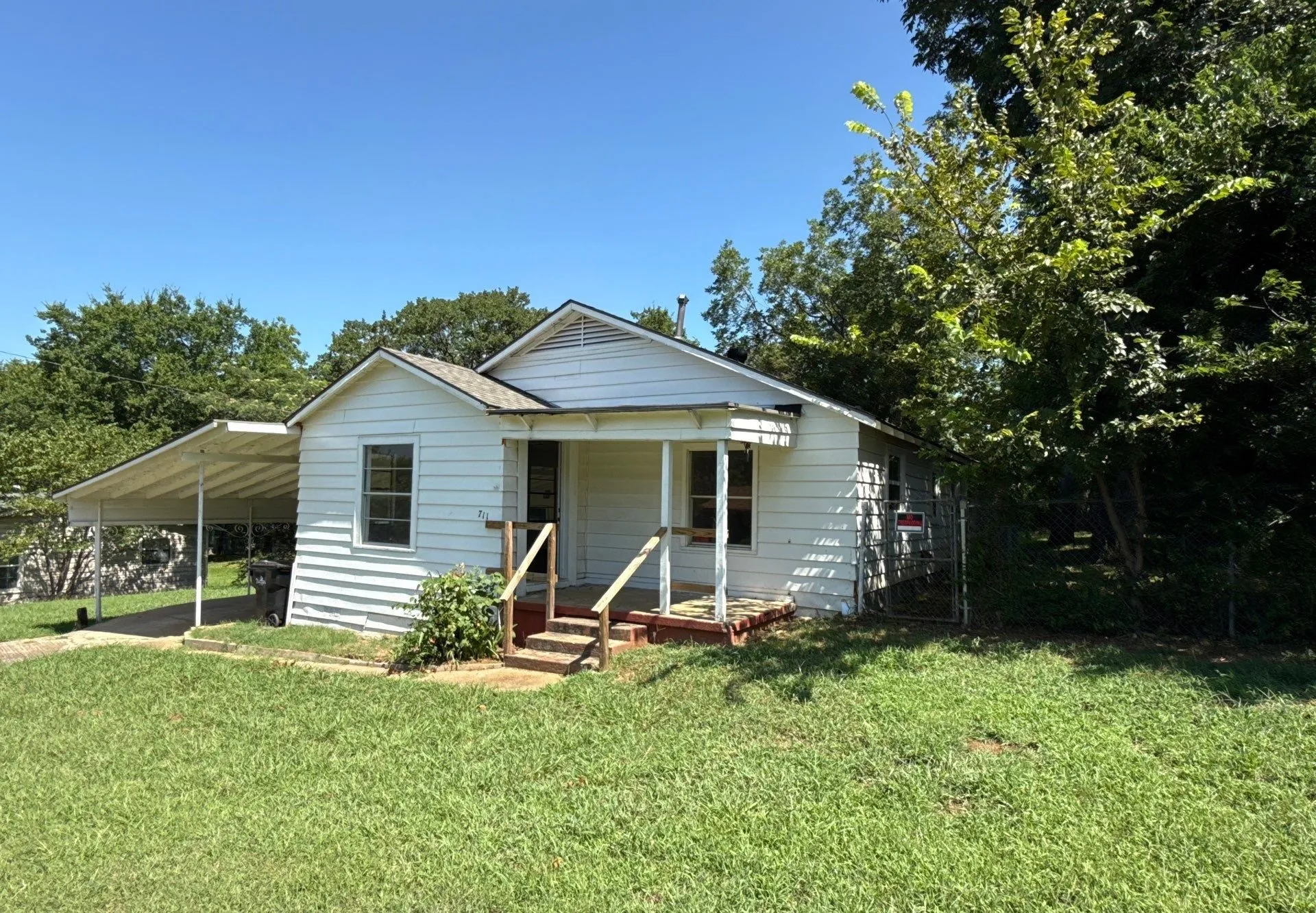 Bungalow-style home with a front lawn, an attached carport, and covered porch