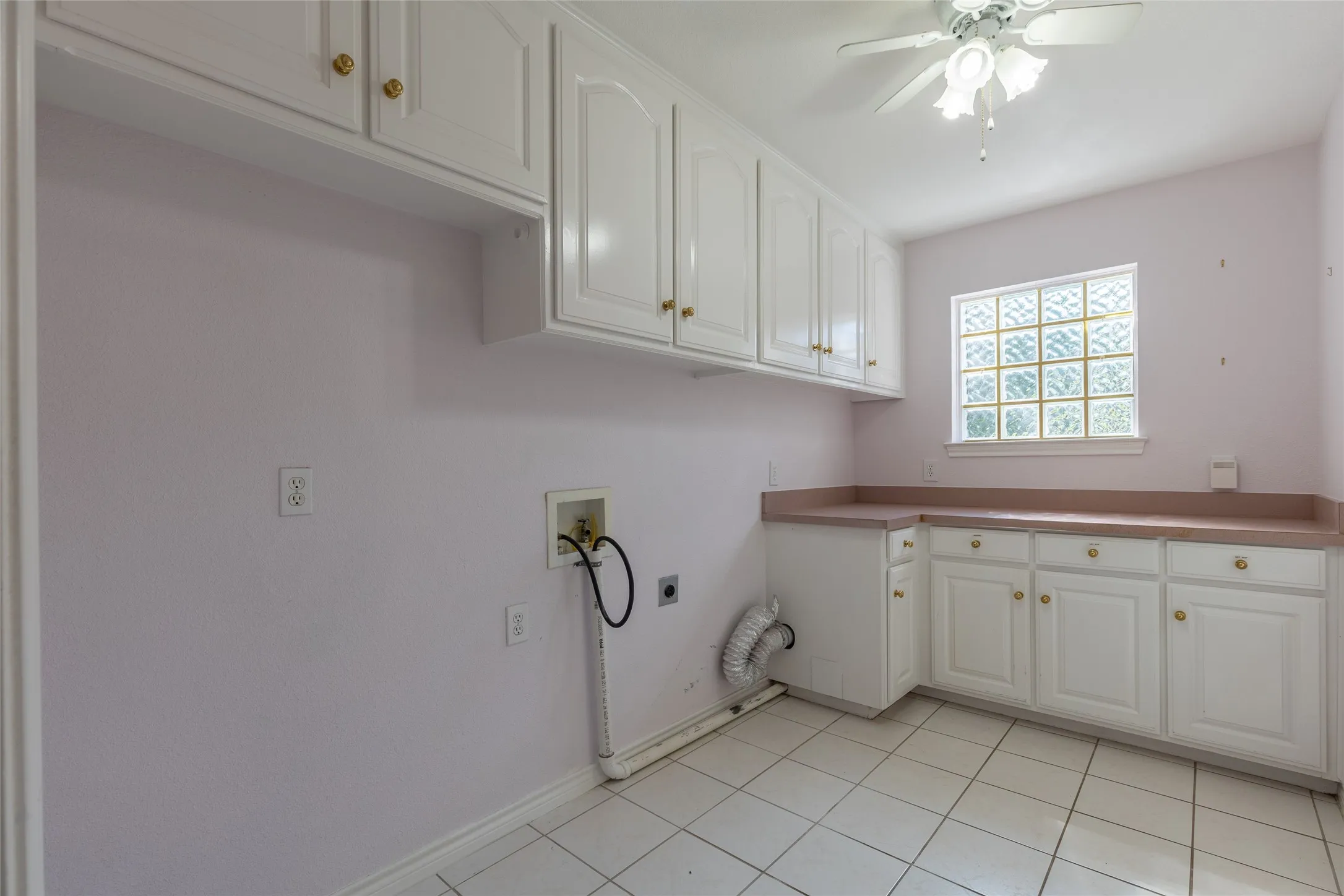 Laundry room with hookup for an electric dryer, hookup for a washing machine, cabinet space, light tile patterned floors, and ceiling fan
