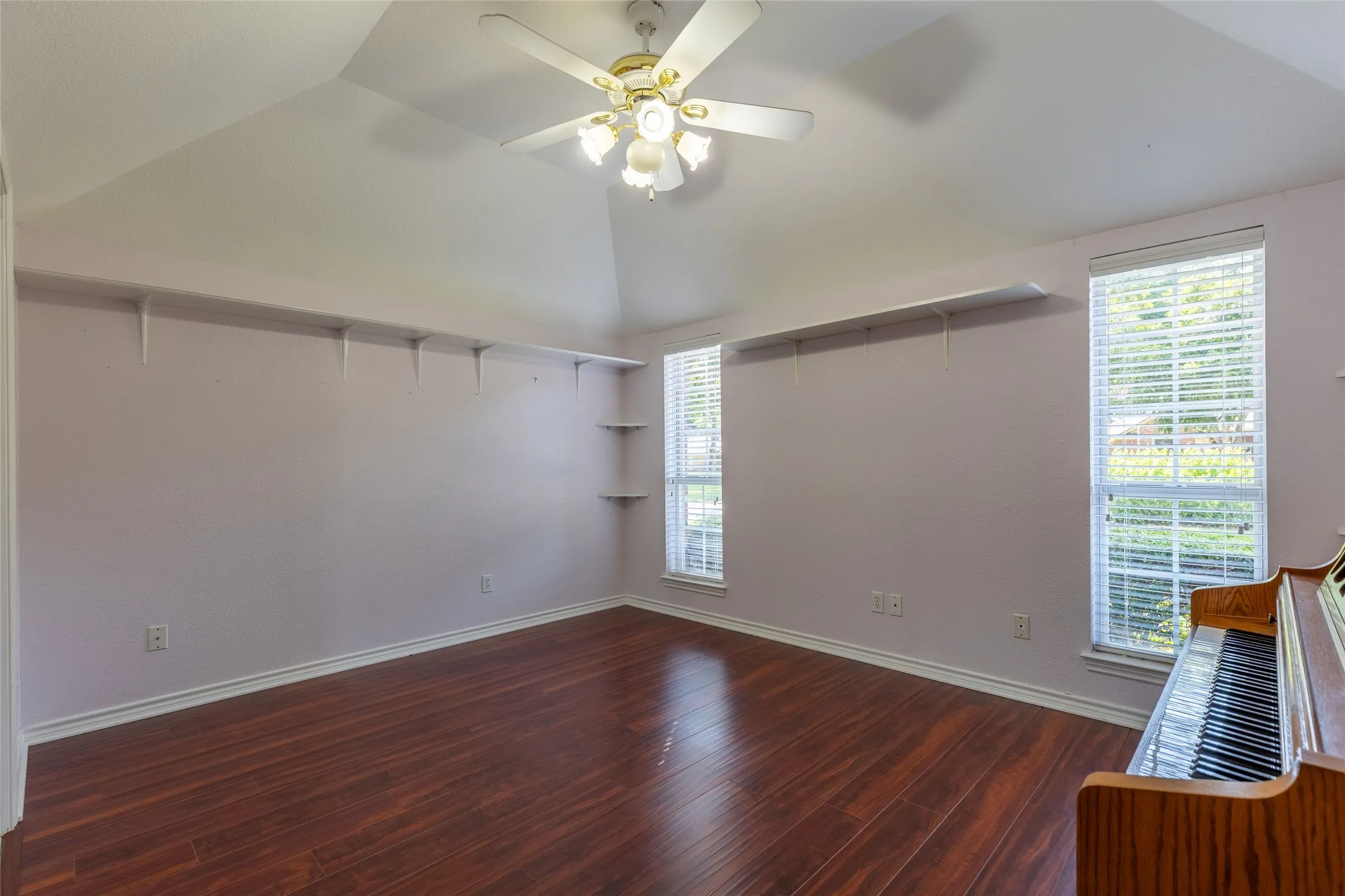 Spare room featuring lofted ceiling, wood finished floors, and a ceiling fan