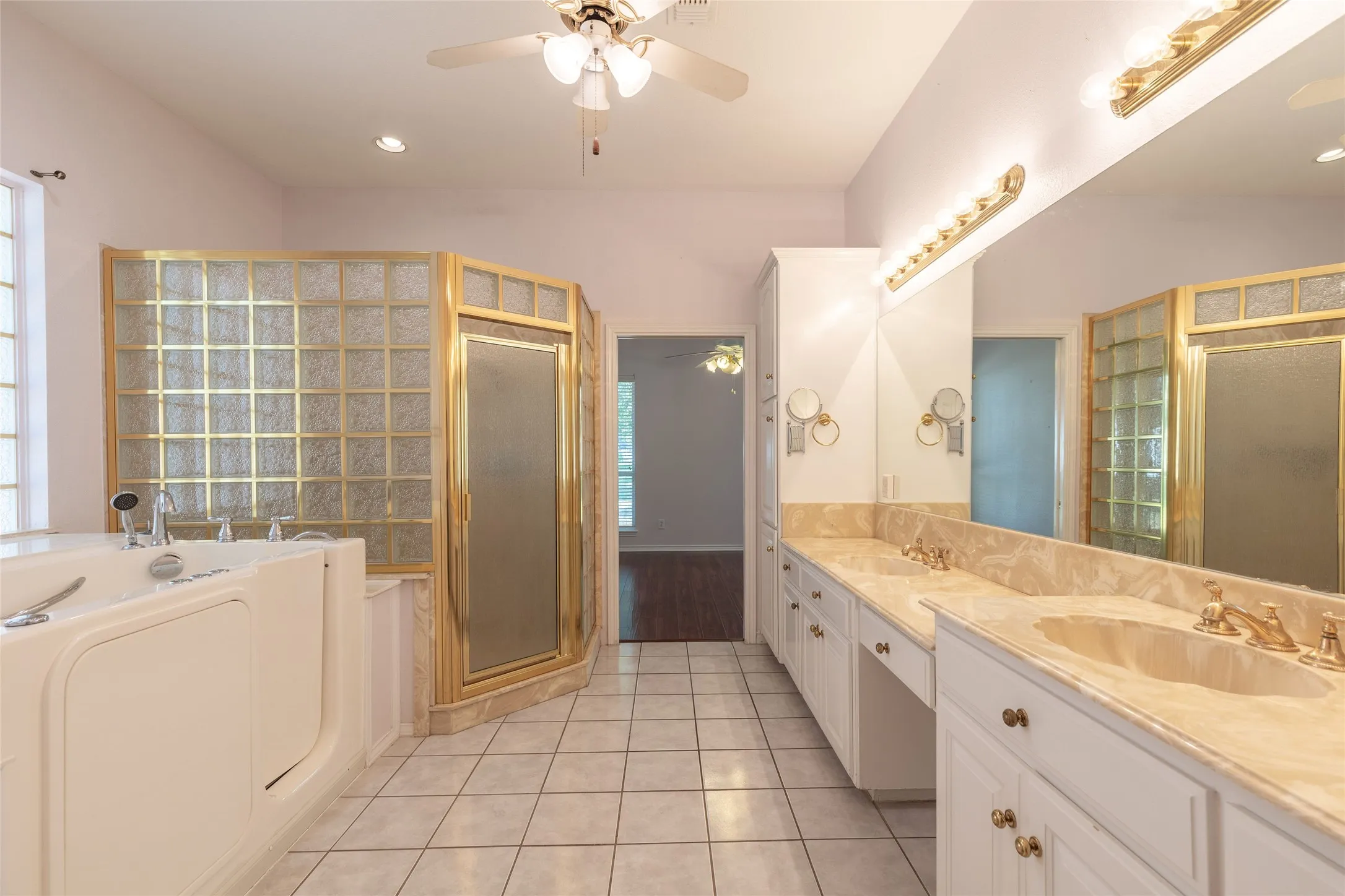 Bathroom with double vanity, a shower stall, a ceiling fan, a bath, and tile patterned flooring