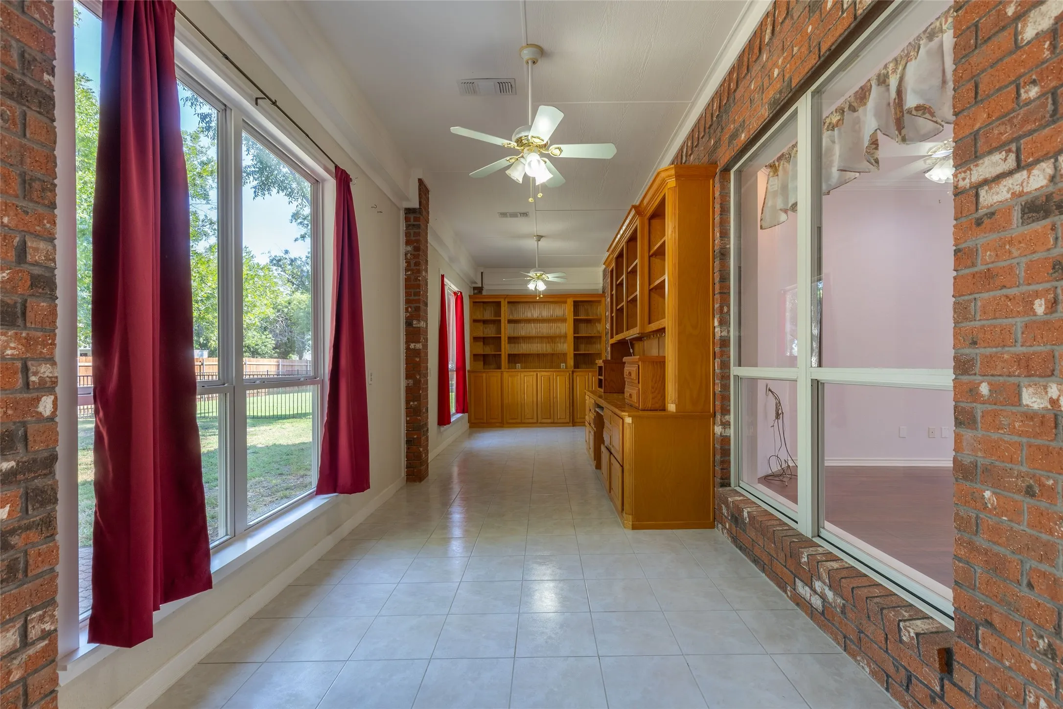 Corridor featuring brick wall and light tile patterned flooring