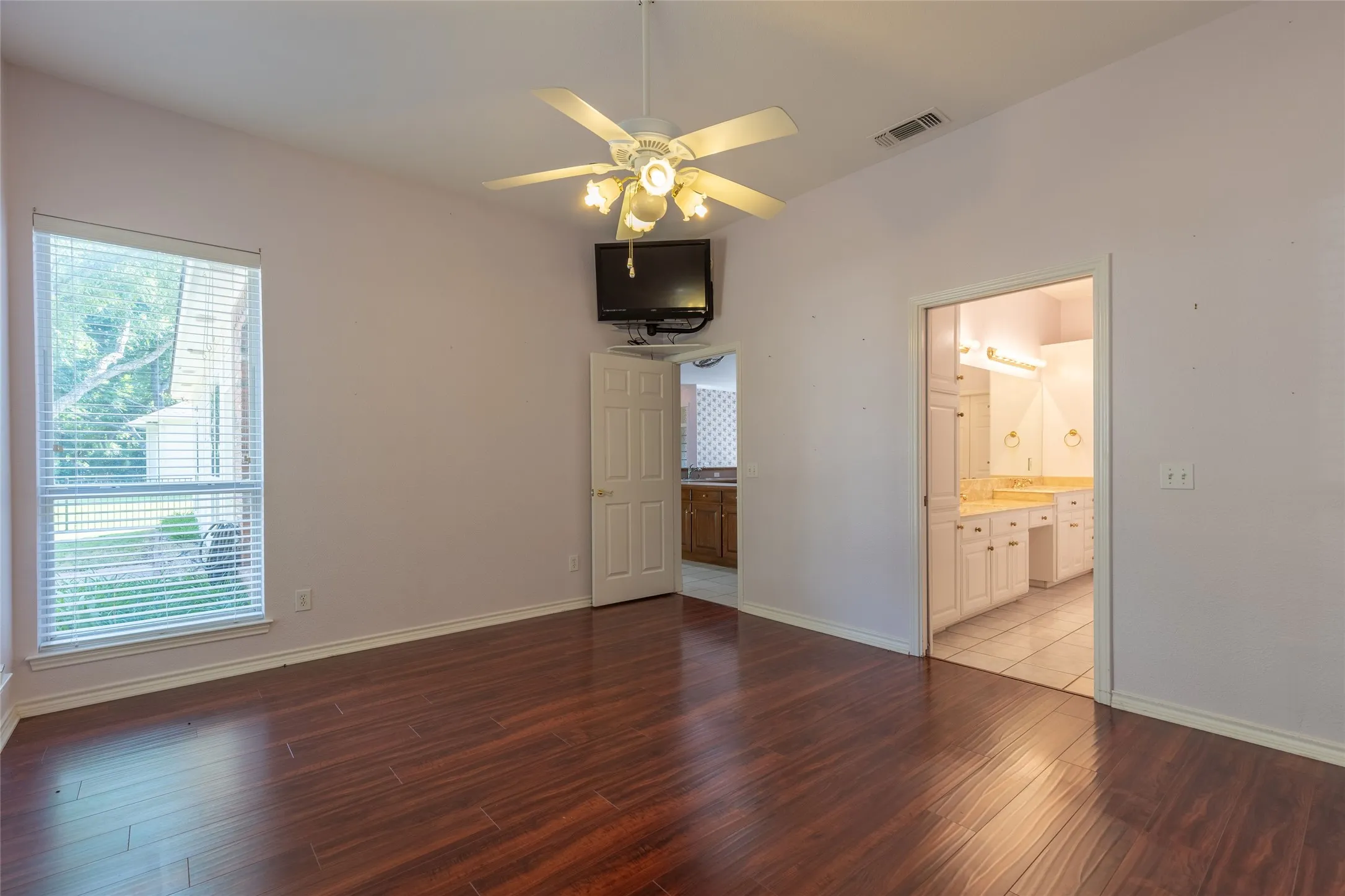Unfurnished bedroom with wood finished floors and ensuite bathroom