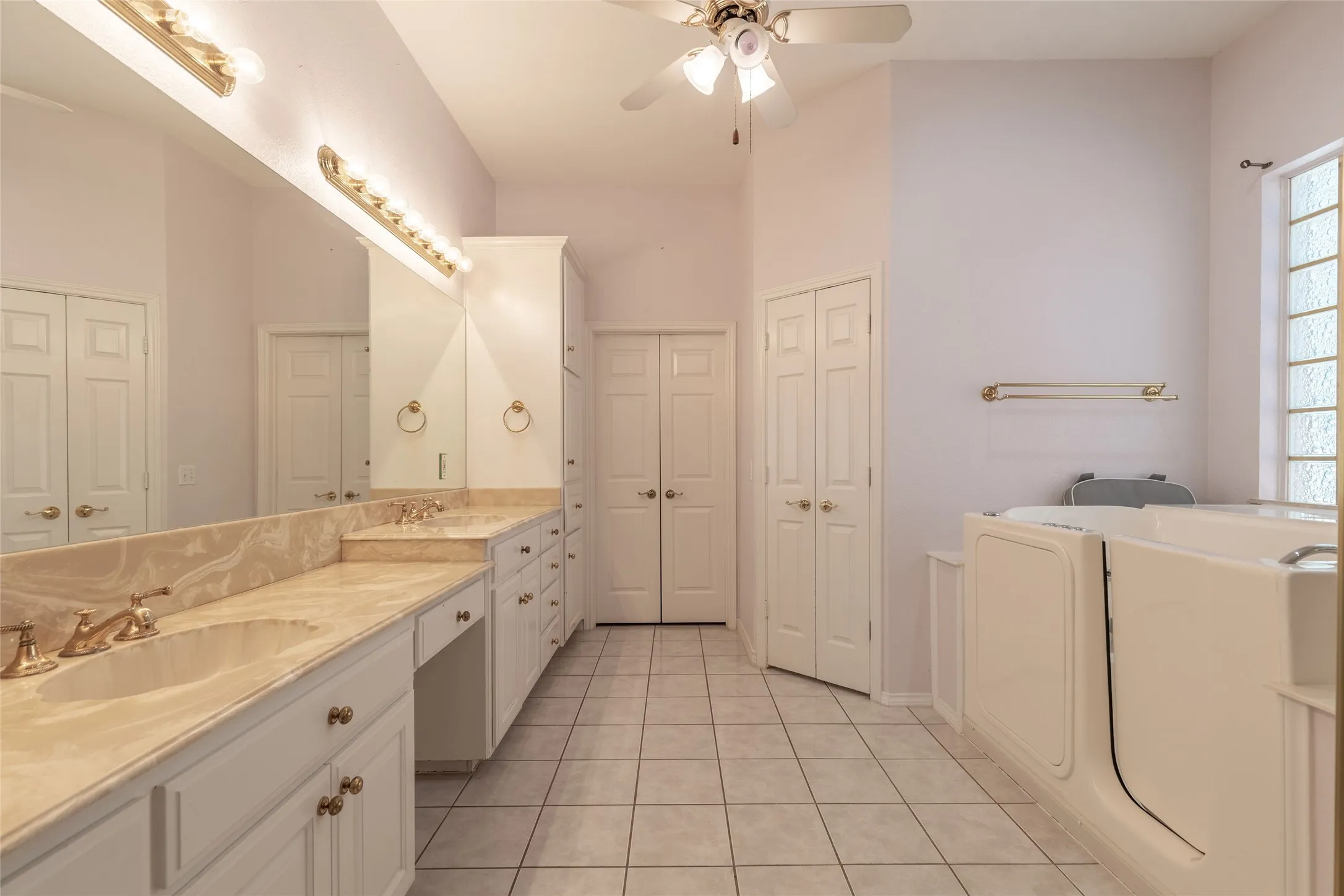 Full bath featuring a closet, double vanity, tile patterned floors, and a garden tub