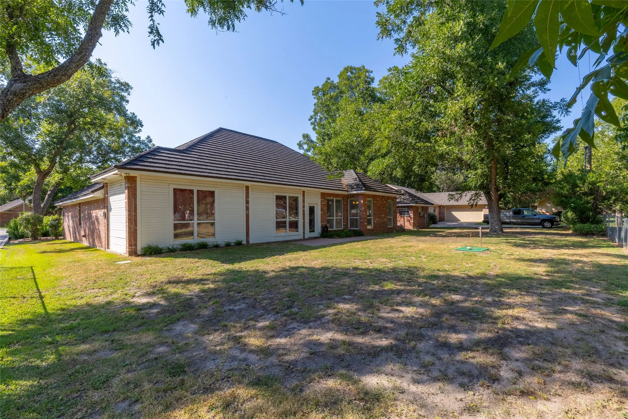 Back of house featuring brick siding and a lawn