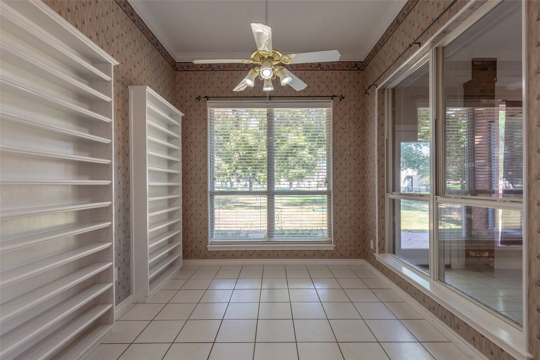 Unfurnished dining area featuring wallpapered walls, light tile patterned floors, ornamental molding, and a ceiling fan