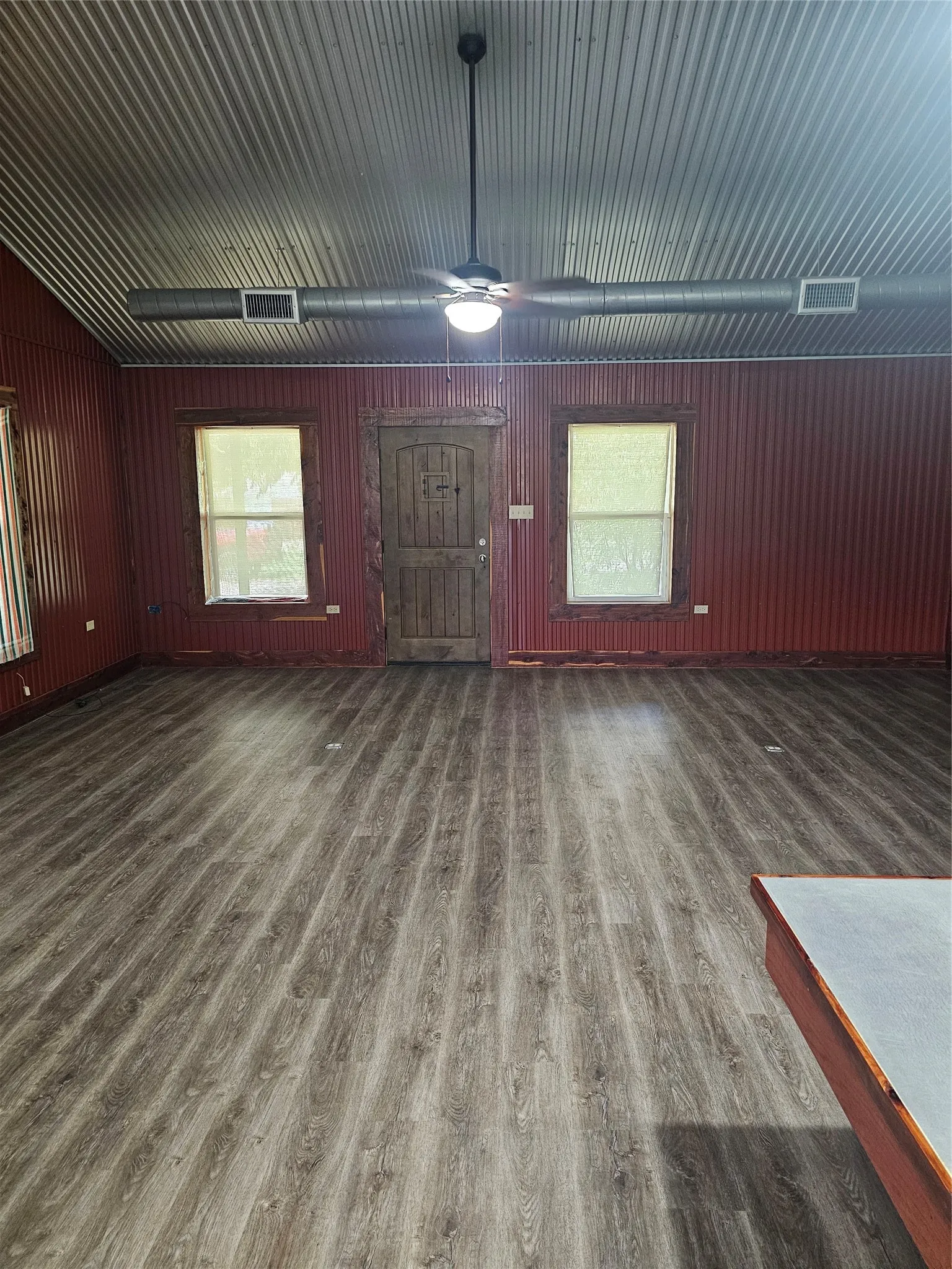 Unfurnished living room featuring wood finished floors, a ceiling fan, and healthy amount of natural light