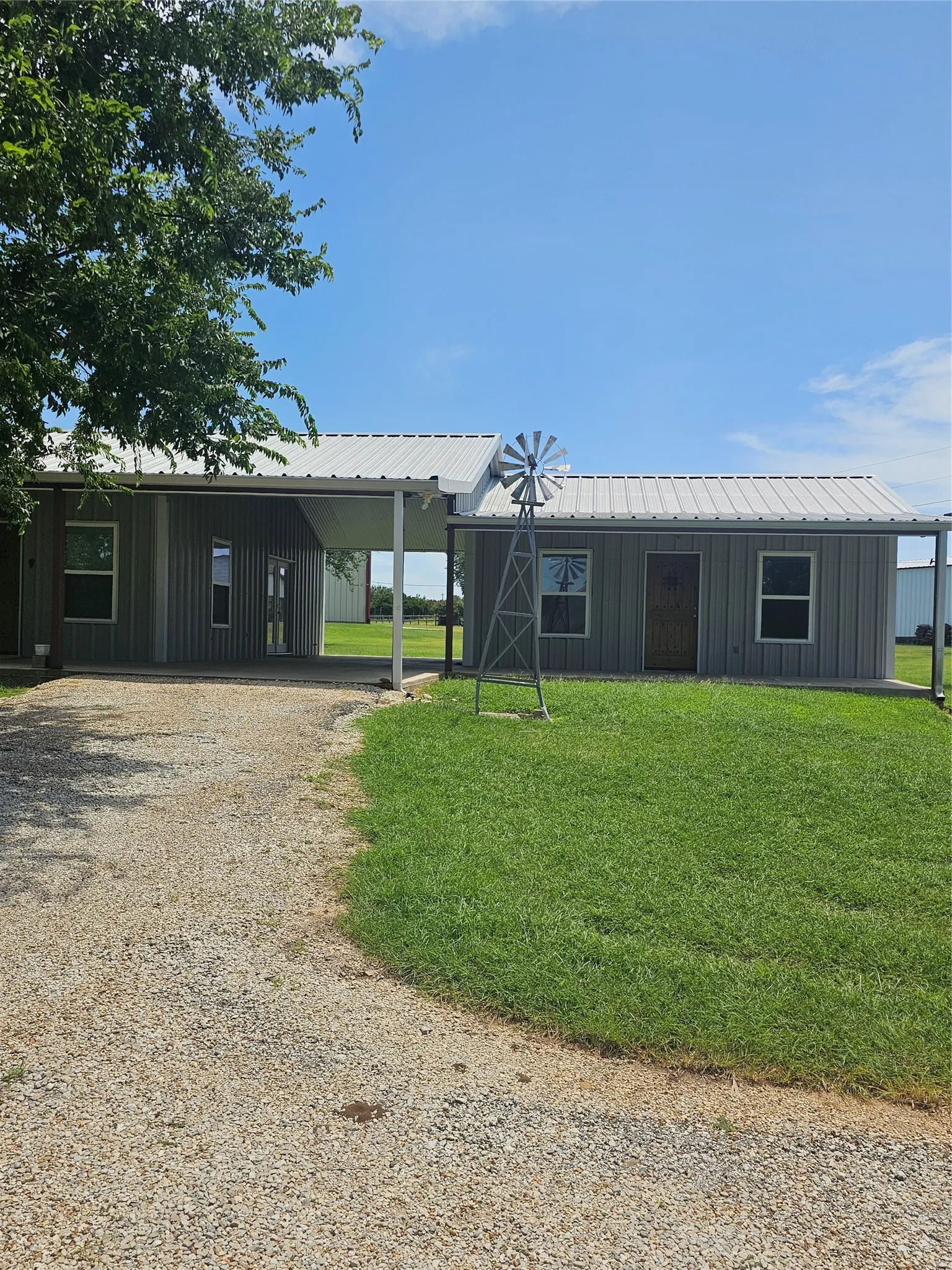 View of front of property featuring a carport, gravel driveway, metal siding and roof.