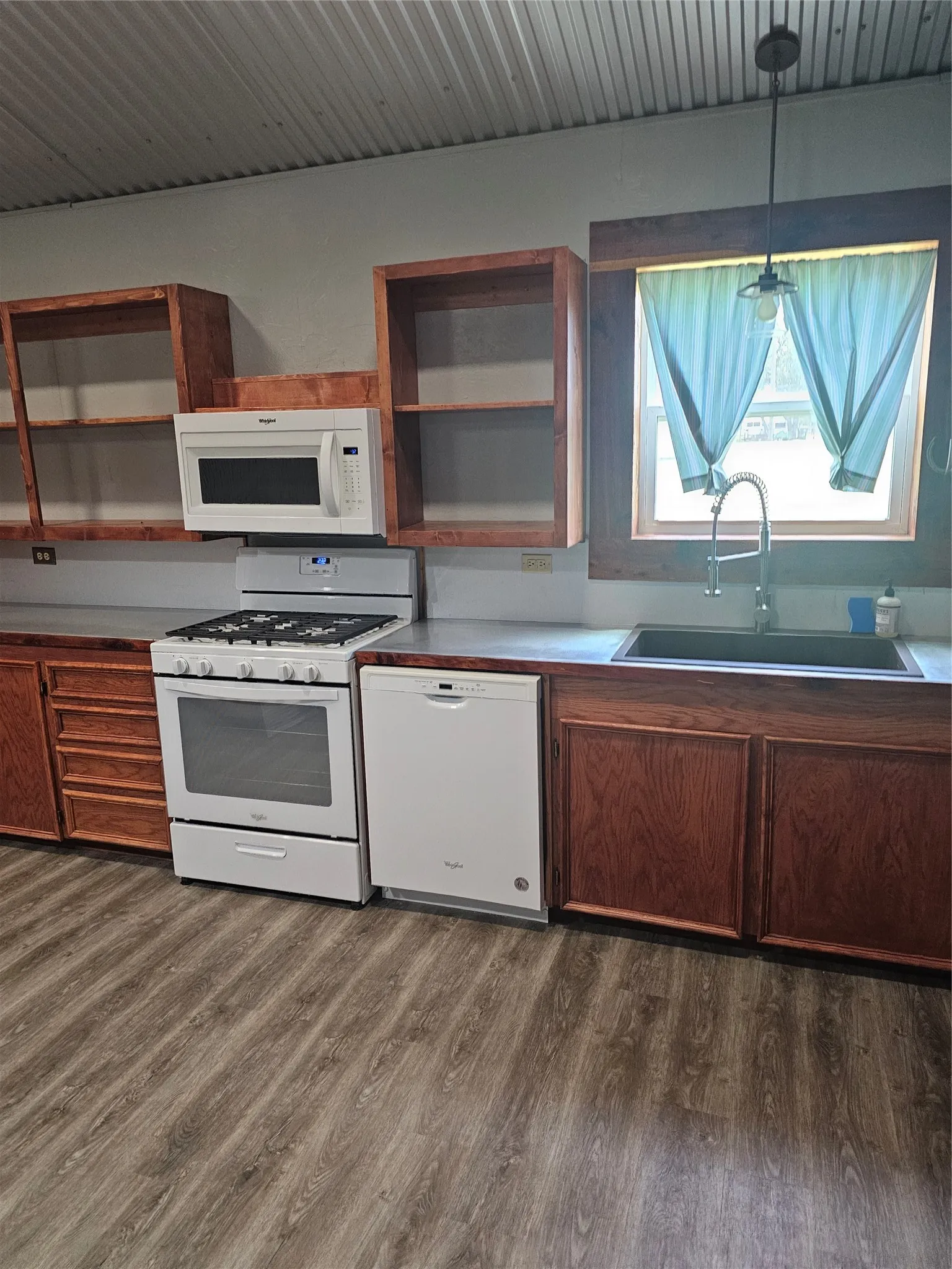 Kitchen with stove, dishwasher, open shelves, and dark wood-style flooring