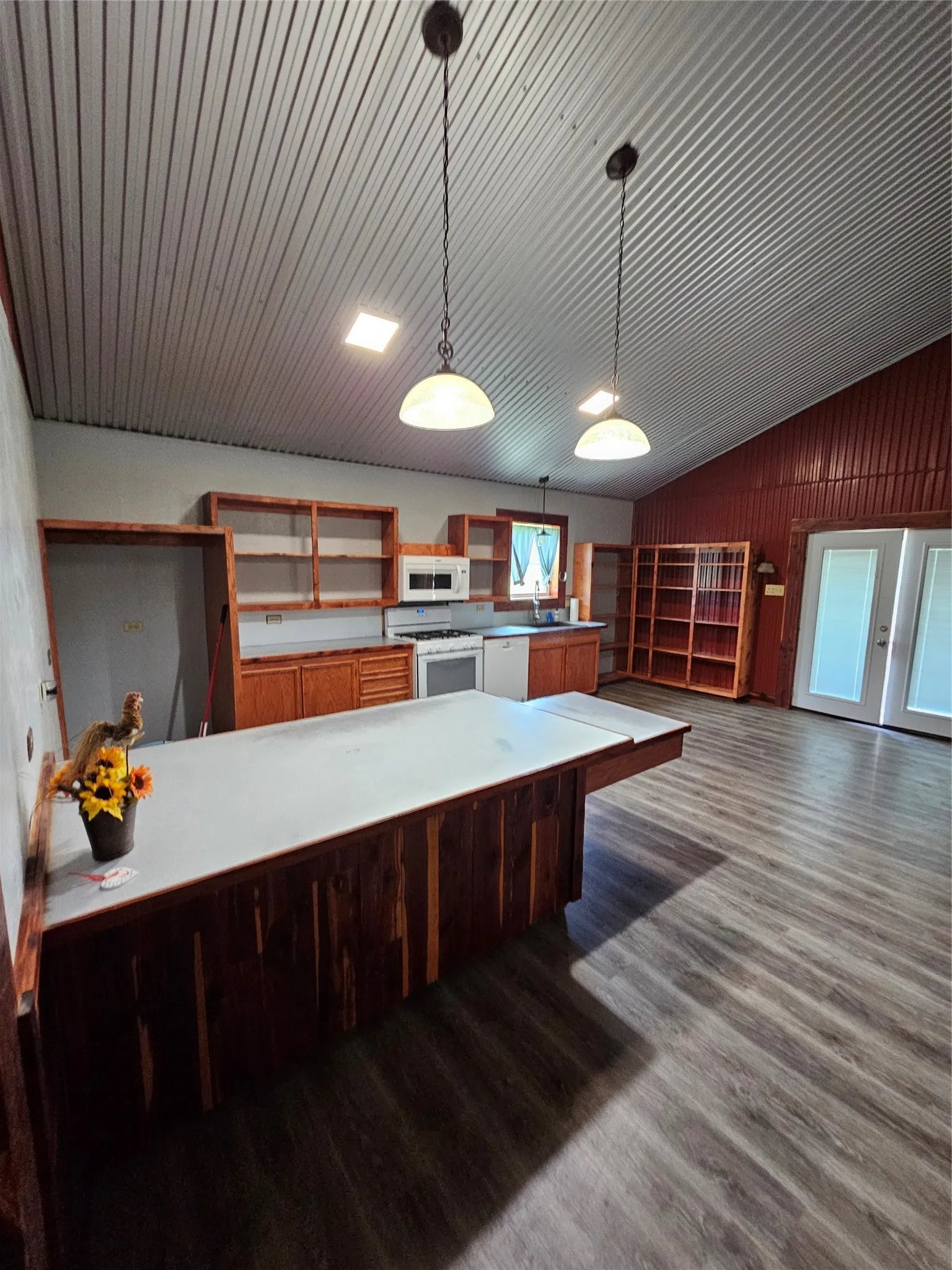 Kitchen featuring lofted ceiling, dark wood-style flooring, range, pendant lighting, and brown cabinetry