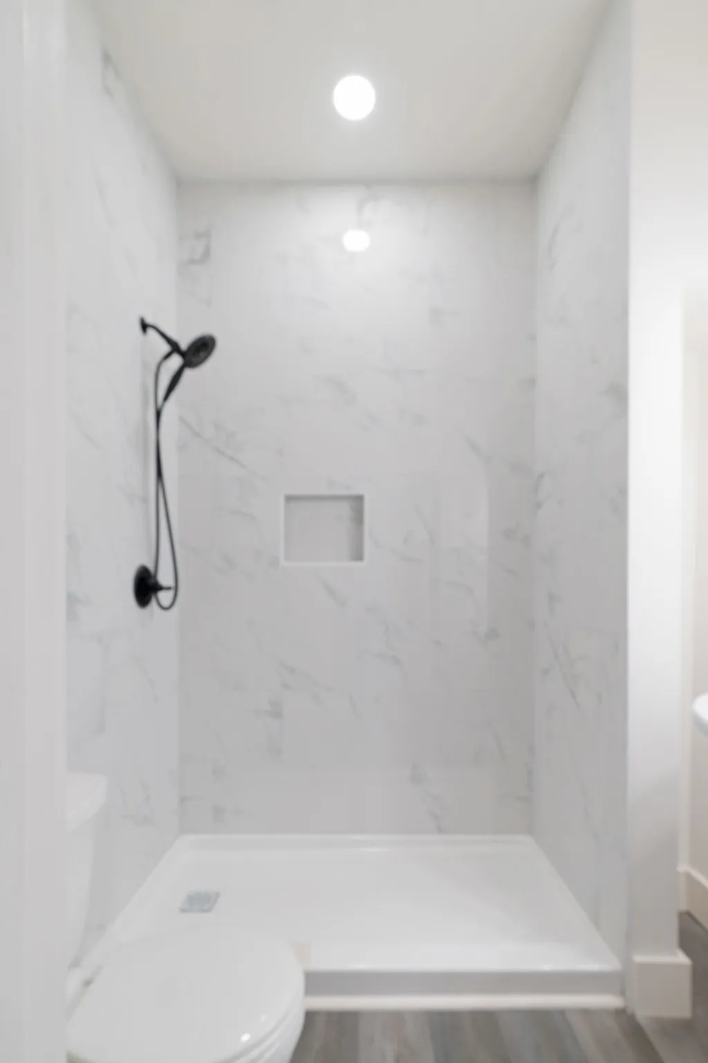 Full bath featuring a walk in shower, wood finished floors, and recessed lighting