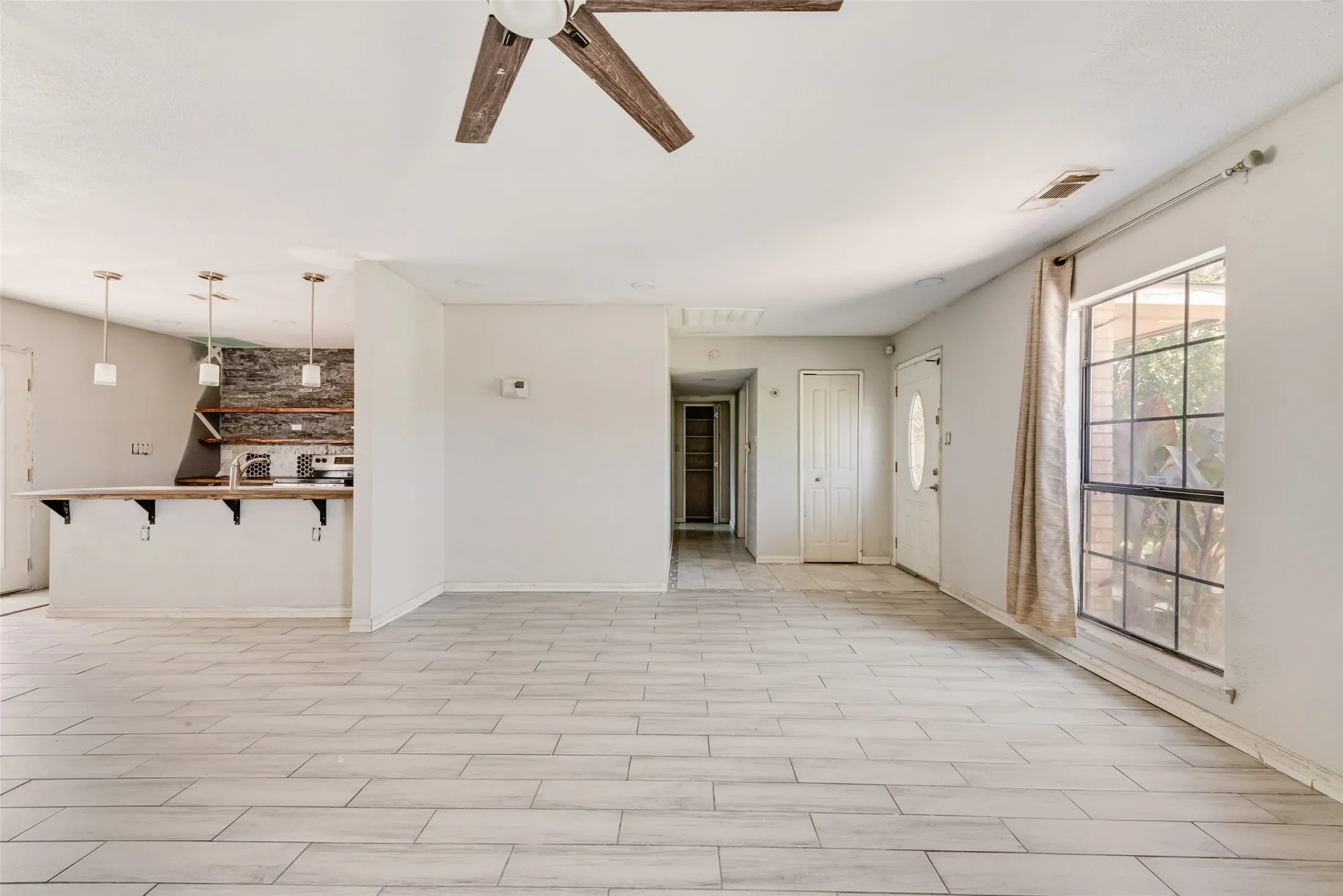 Unfurnished living room featuring ceiling fan and baseboards
