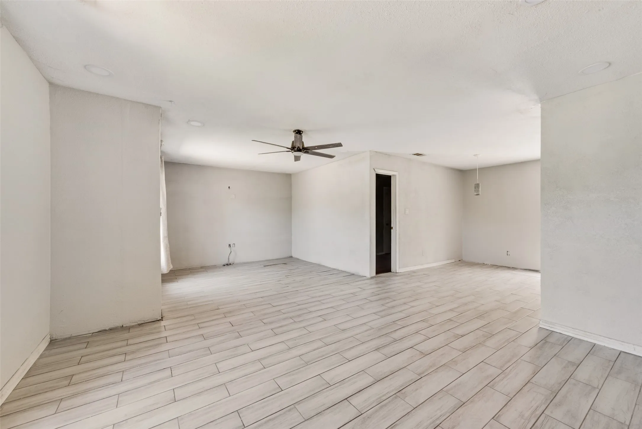 Empty room with a ceiling fan and light wood-style floors