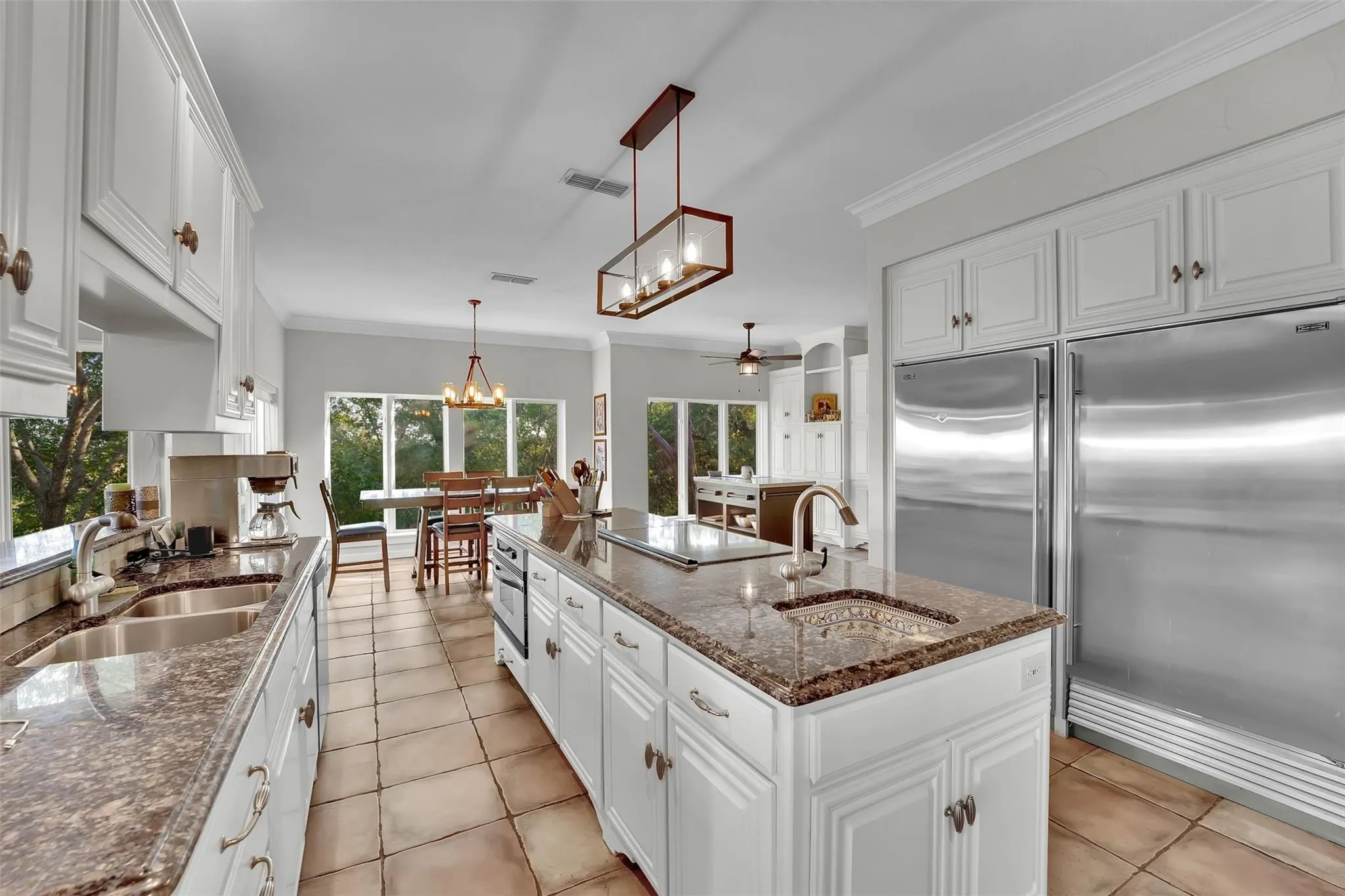 Kitchen with a chandelier, stainless steel appliances, a center island with sink, a ceiling fan, and light tile patterned flooring