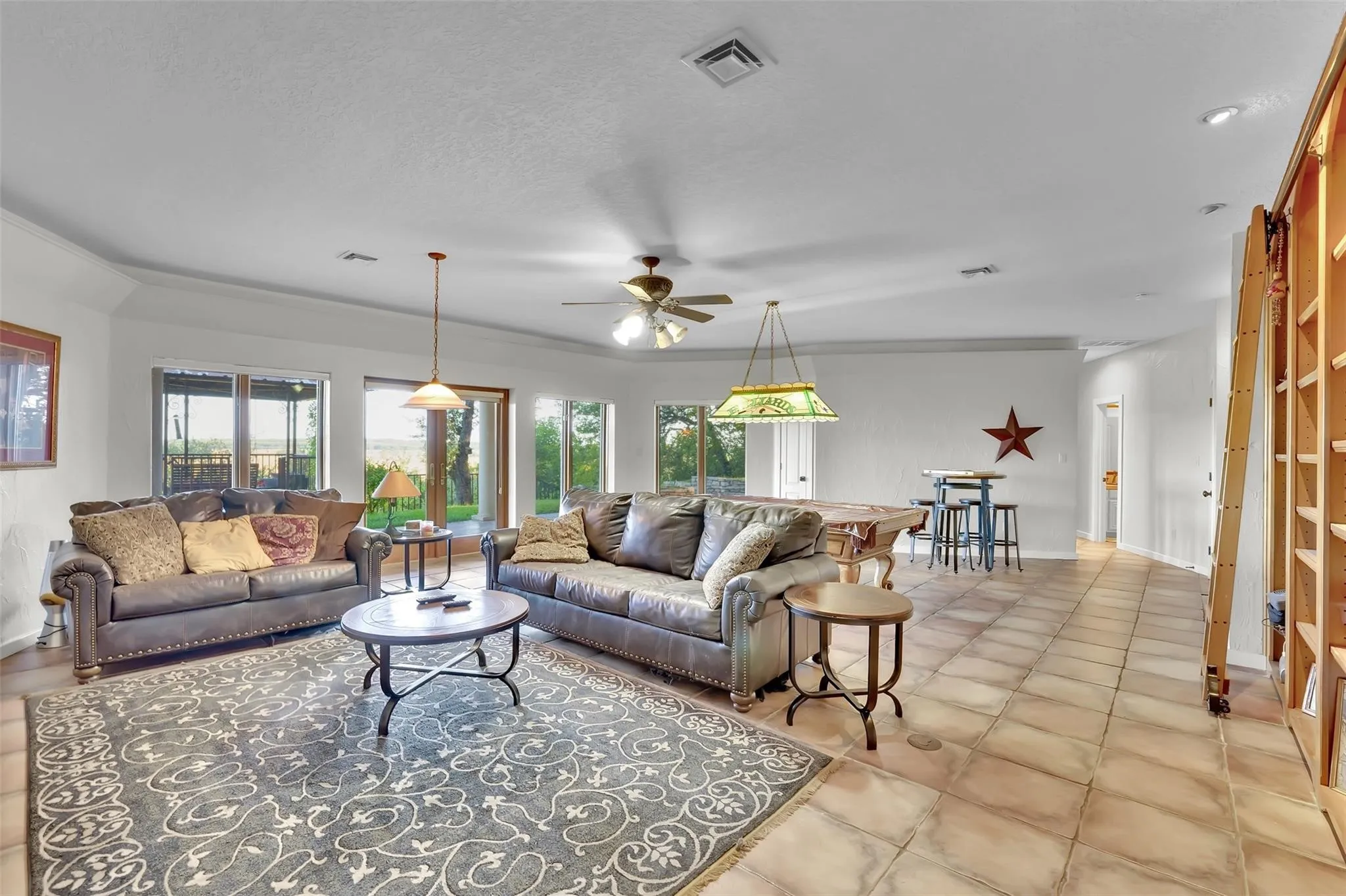 Living room with ceiling fan, plenty of natural light, and light tile patterned floors